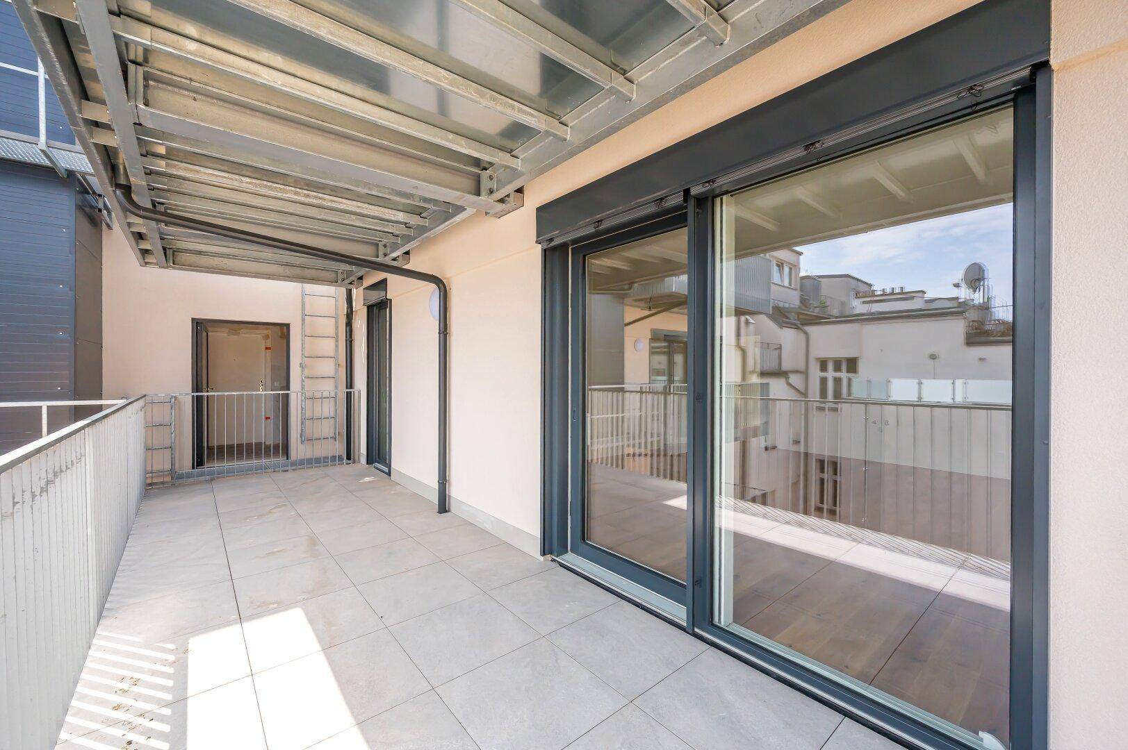 Geräumiger Balkon mit Fliesenboden und Metallgeländer, bietet Platz für Outdoor-Möbel.