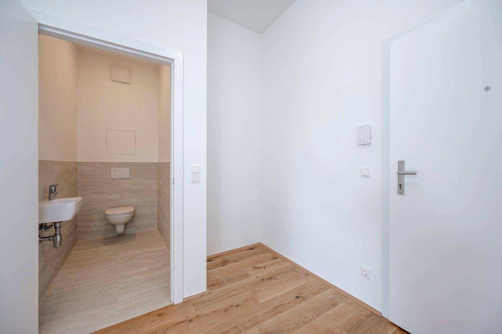 Kleines Gäste-WC mit modernem Waschbecken und wandhängender Toilette, zugänglich vom Flur.