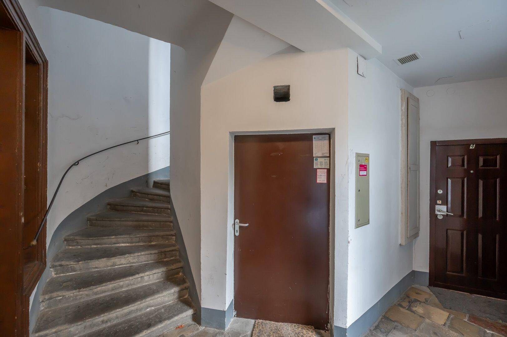 Geschwungener Treppenaufgang in einem Altbau mit einer braunen Tür im Erdgeschoss.
