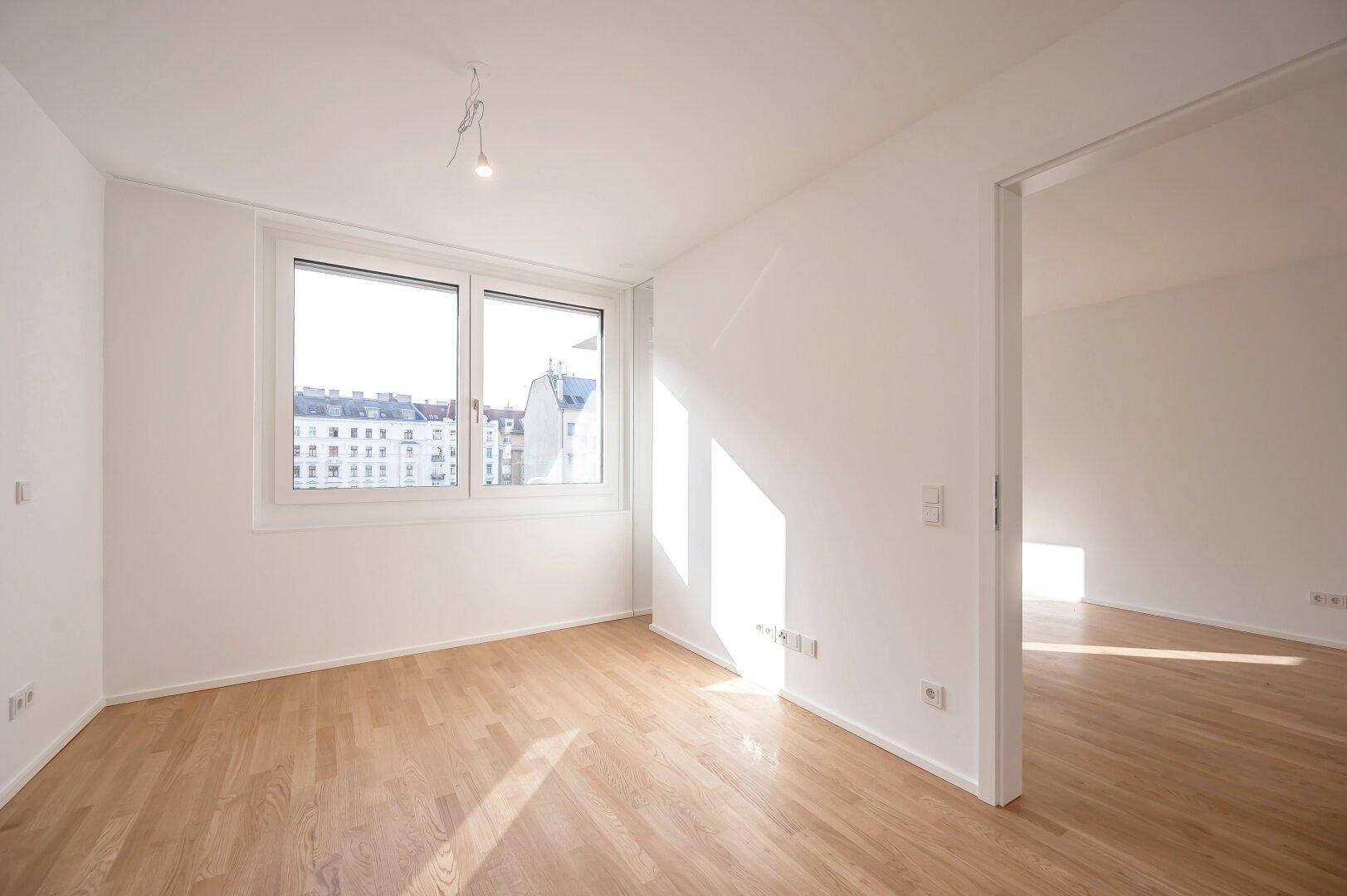 Helles Schlafzimmer mit Holzboden und großem Fenster mit Stadtblick.