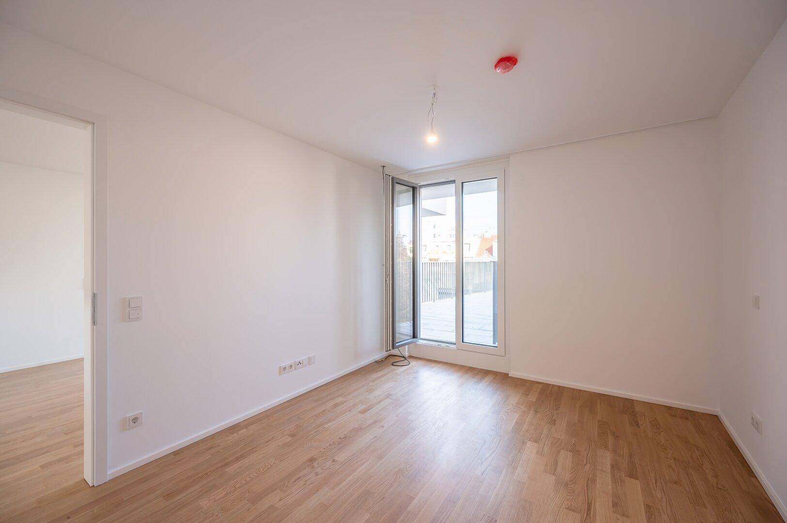 Geräumiges Schlafzimmer mit Holzboden und Zugang zu einem Außenbereich.
