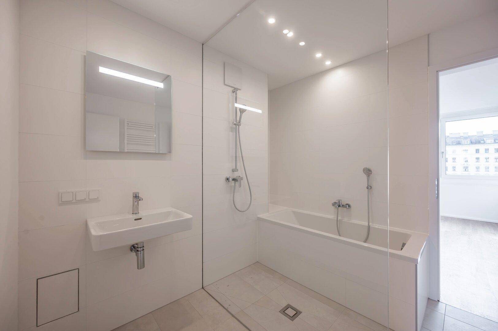 Modernes Badezimmer mit Badewanne, Dusche, Einzelwaschbecken und hellen Fliesen.