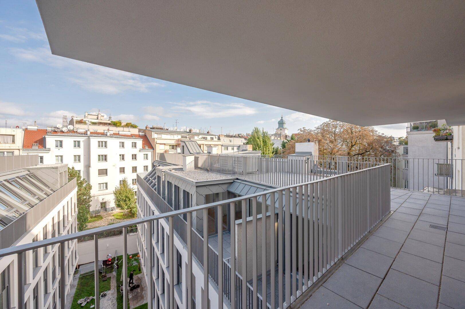 Geräumige Terrasse mit Blick auf den Innenhof und die umliegenden Gebäude der Stadt.