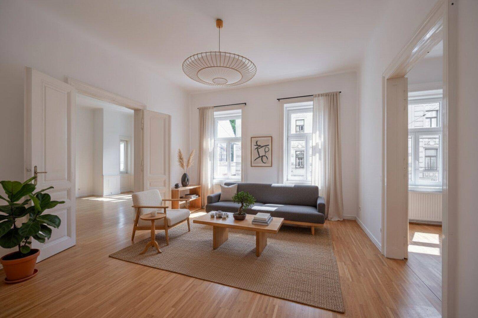 Gemütliches Wohnzimmer mit Sofa, Couchtisch und hellem Parkettboden, verbunden mit weiteren Räumen.