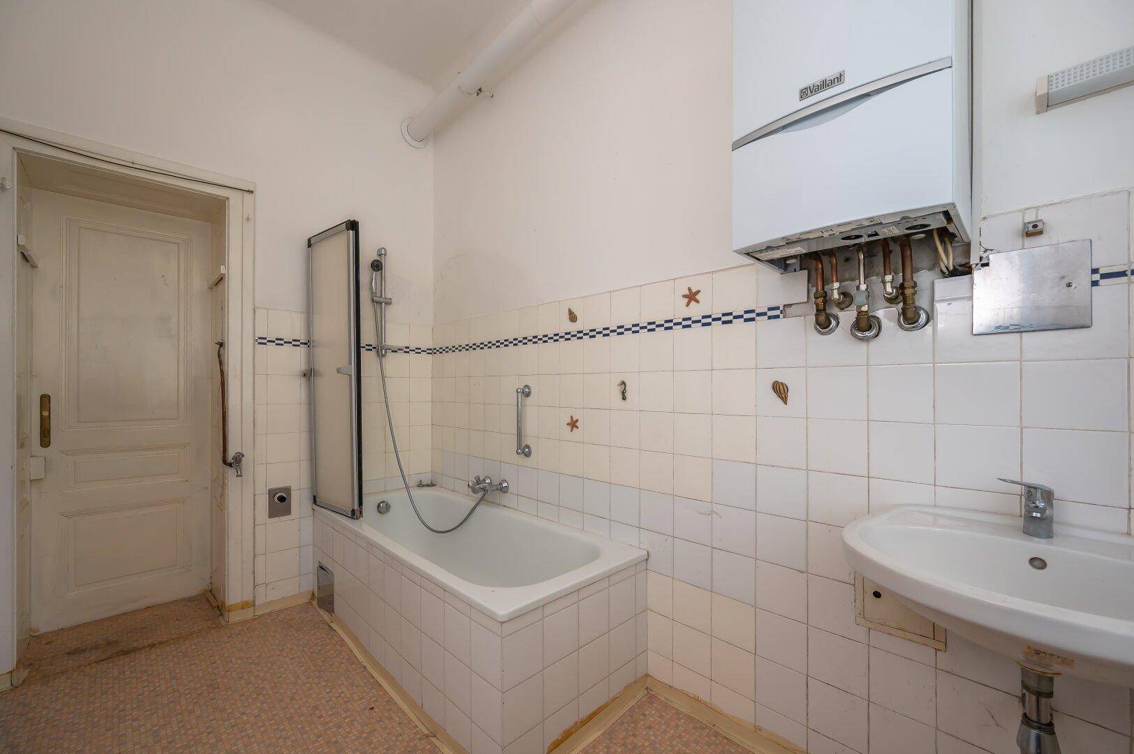 Badezimmer mit Badewanne, Duschabtrennung und Wandfliesen im Vintage-Stil.