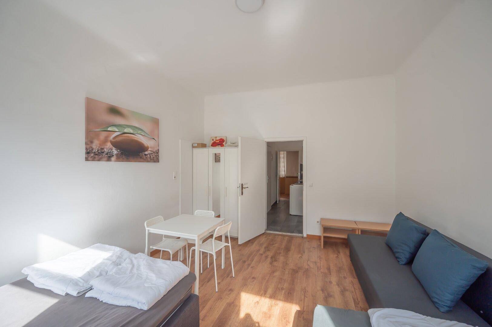 Geräumiges Schlafzimmer mit Sofa, Kleiderschrank und Zugang zu weiteren Räumen.