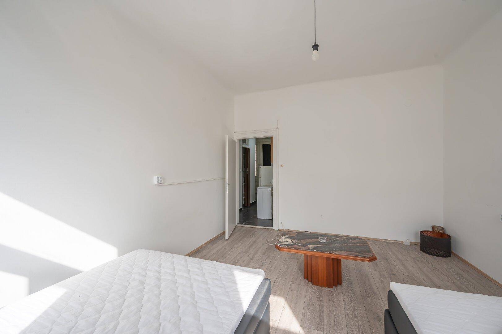 Geräumiges Schlafzimmer mit hellem Boden und Zugang zu einem weiteren Raum, ideal für flexible Nutzung.