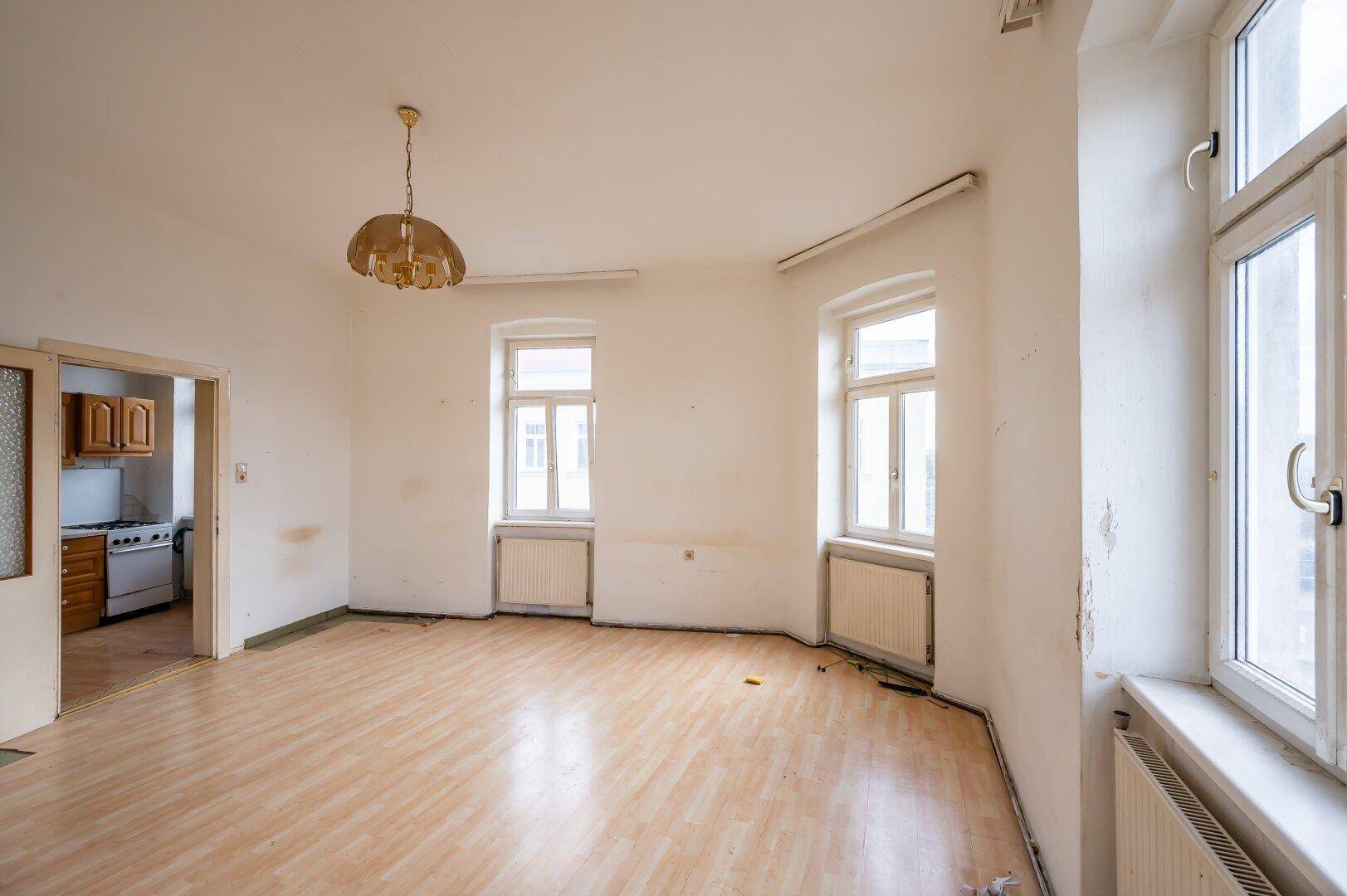 Heller Raum mit Laminatboden und Blick in die angrenzende Küche, ideal für einen Wohn-Essbereich.