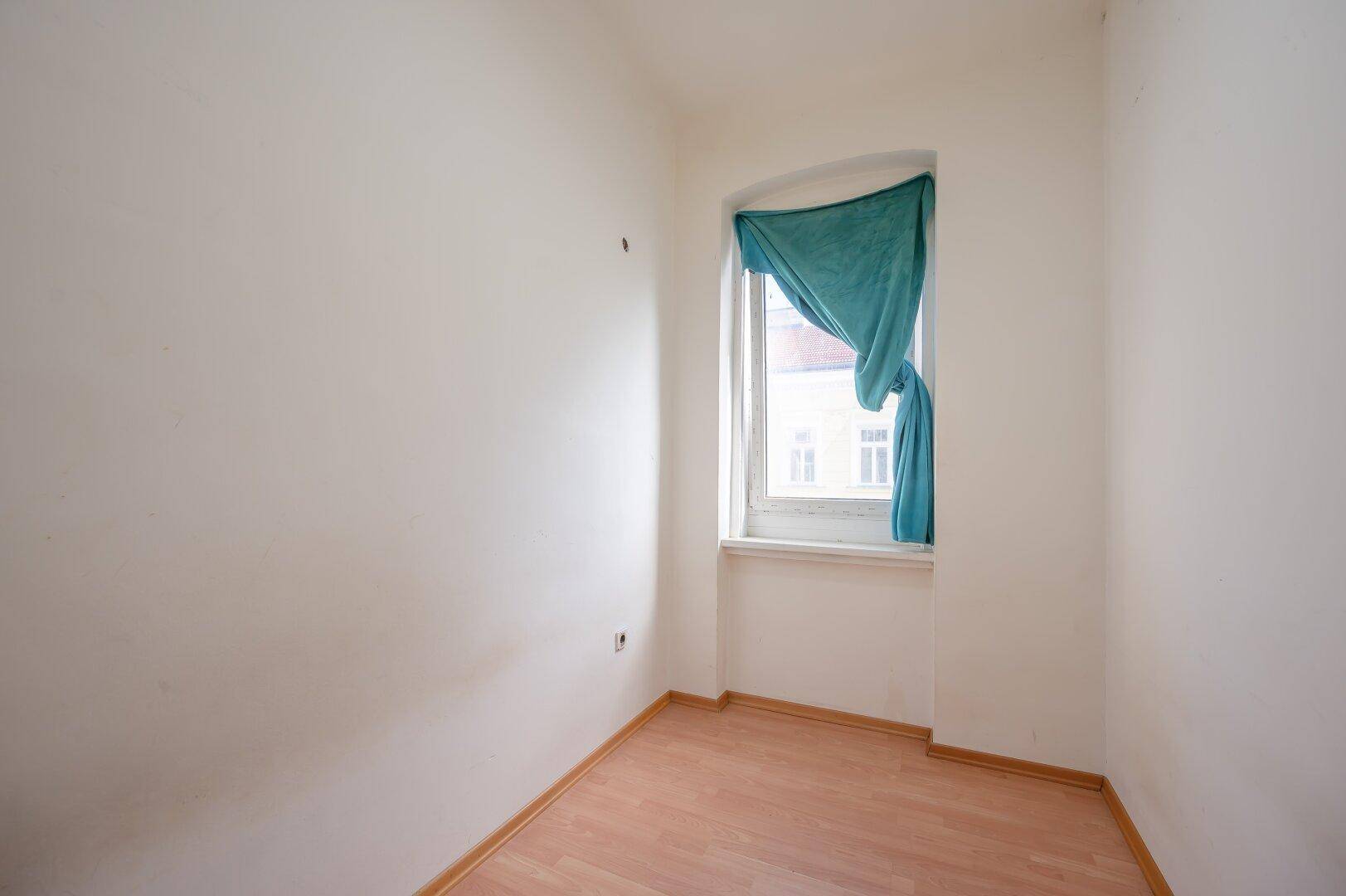 Kleines, helles Zimmer mit Laminatboden und einem Fenster, ideal als Schlafzimmer oder Büro.