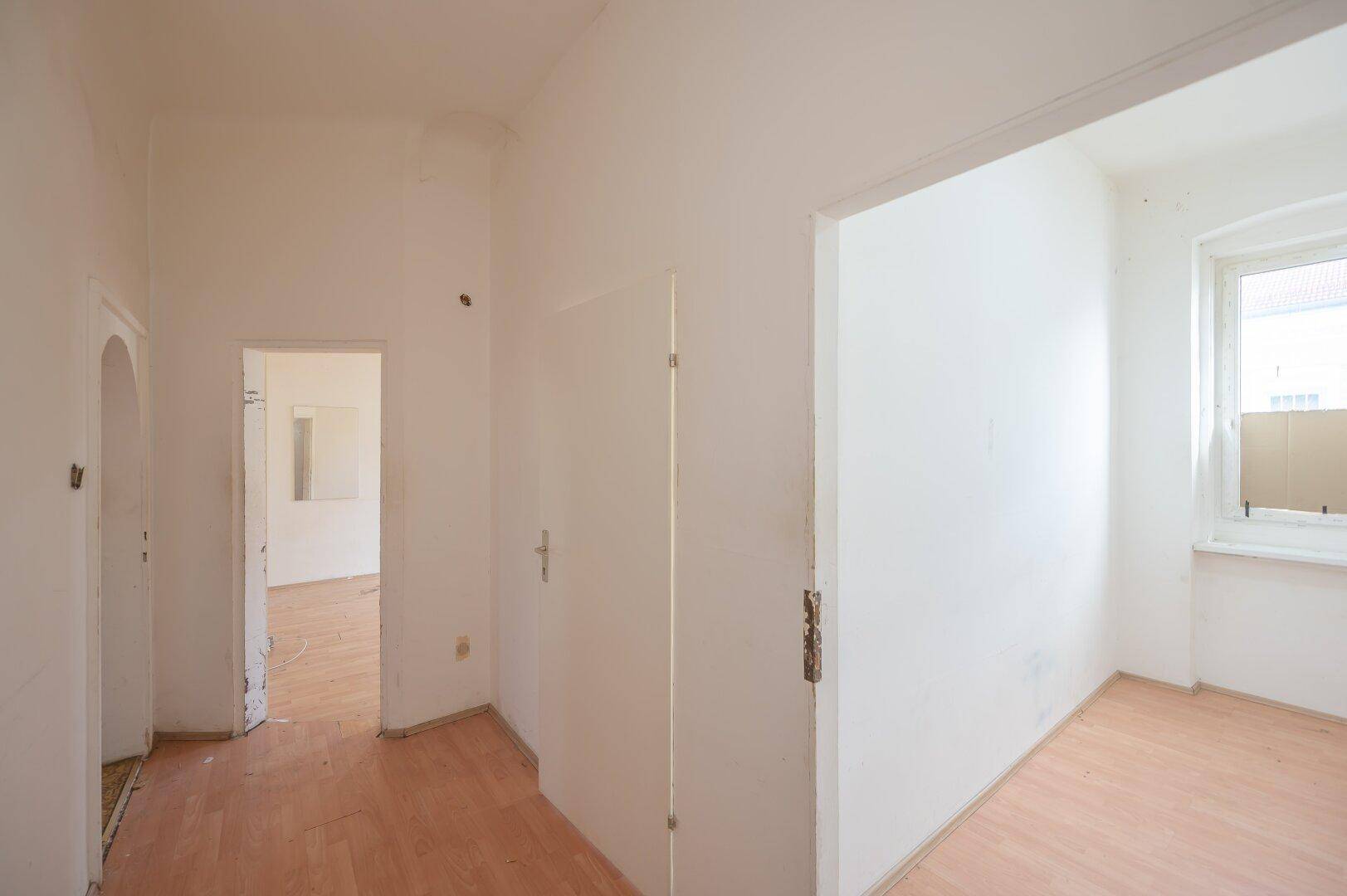 Heller Flur mit Laminatboden und einem Fenster, der den Zugang zu weiteren Räumen ermöglicht.