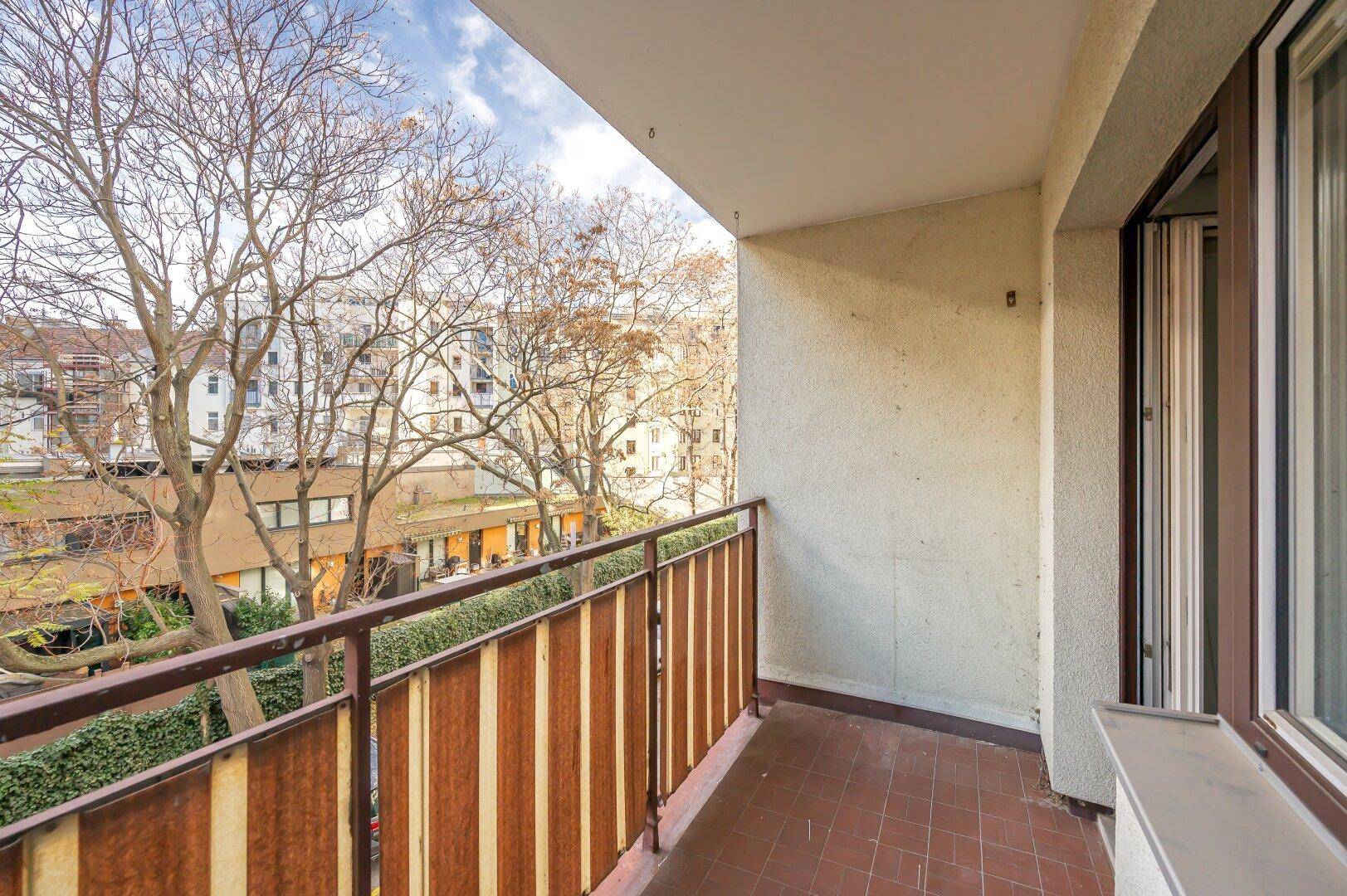 Schmaler Balkon mit Blick ins Grüne und auf die Nachbarschaft, mit einfacher Fliesenboden.