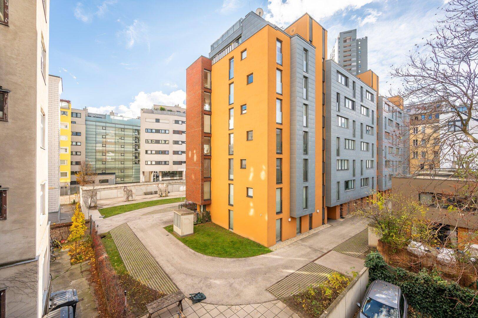 Moderne Architektur des Wohngebäudes mit orangefarbener Fassade und großen Fenstern.