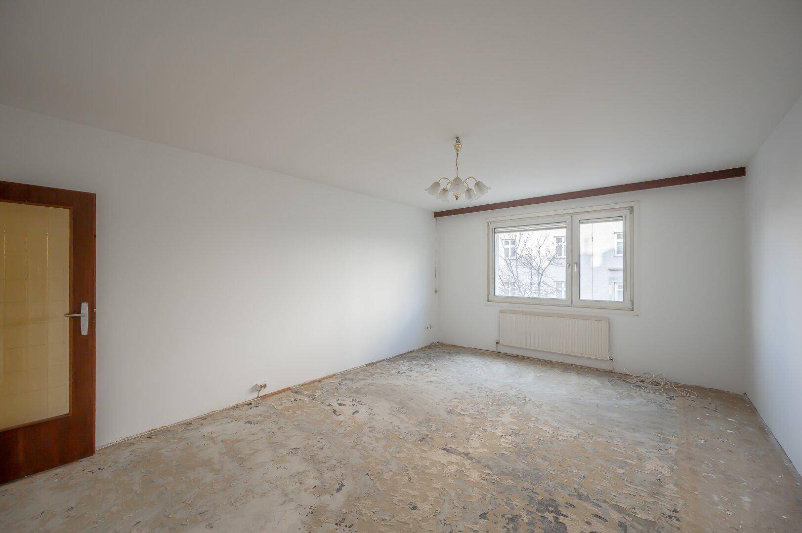 Helles Zimmer mit großem Fenster und einfacher Deckenleuchte, ideal für individuelle Gestaltung.