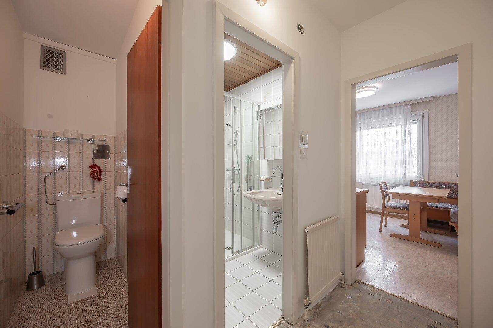 Separates WC mit Haltegriffen und einfacher Ausstattung, angrenzend an den Duschbereich.