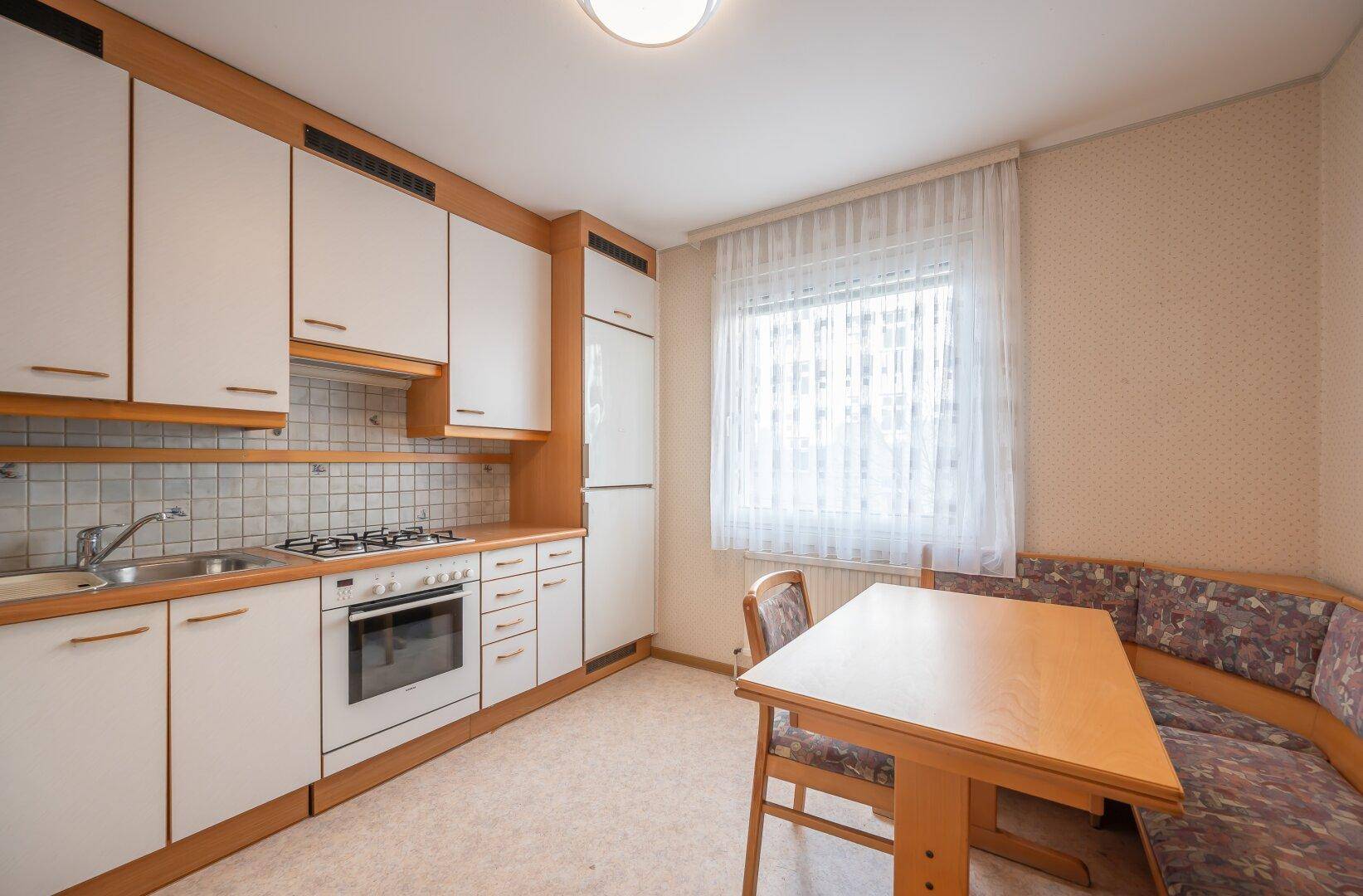 Funktionale Einbauküche mit Essbereich und Fenster, ausgestattet mit Gasherd und Kühlschrank.