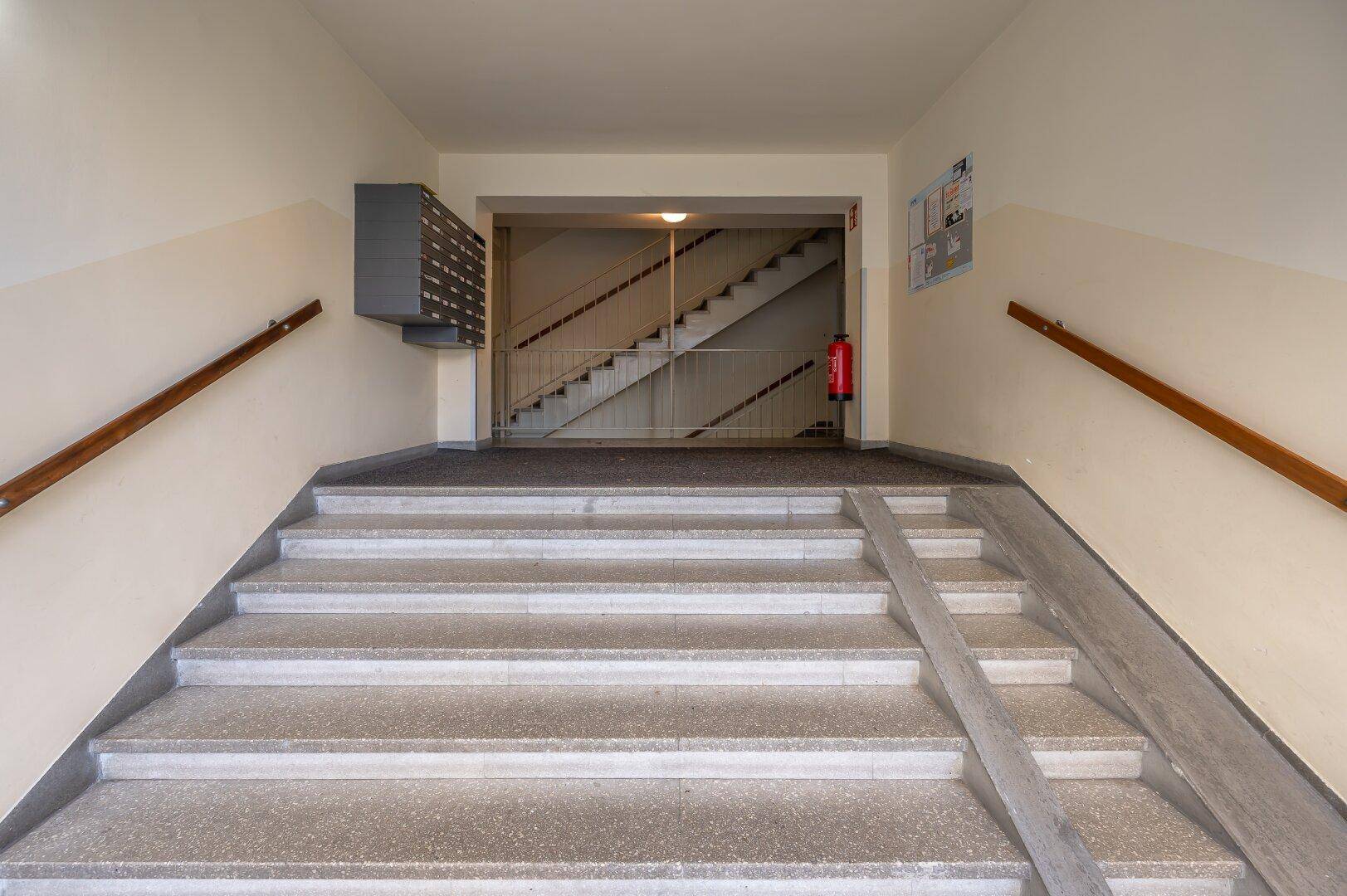 Eingangsbereich eines Gebäudes mit Treppe und Rampe für Barrierefreiheit.