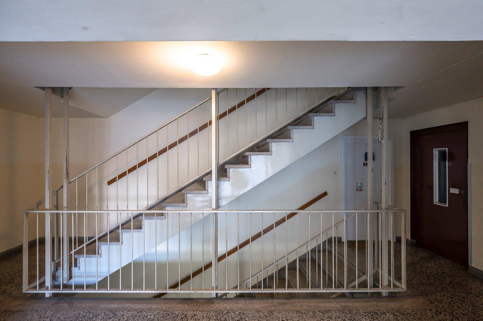 Treppenhaus mit Metallgeländer und Holzhandläufen, das die Stockwerke verbindet.