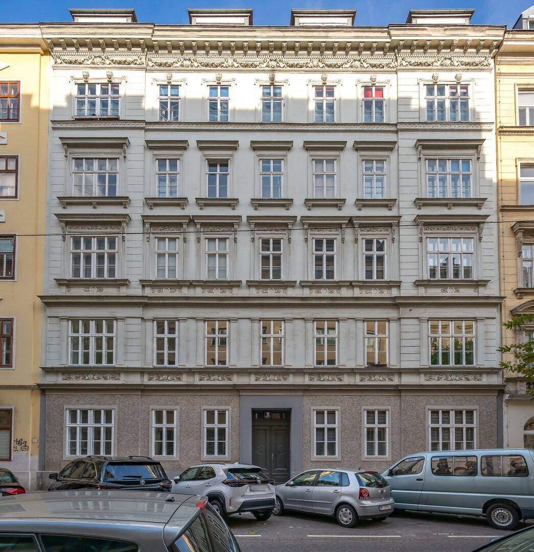 Klassische Fassade eines Mehrfamilienhauses mit vielen Fenstern und architektonischen Details.