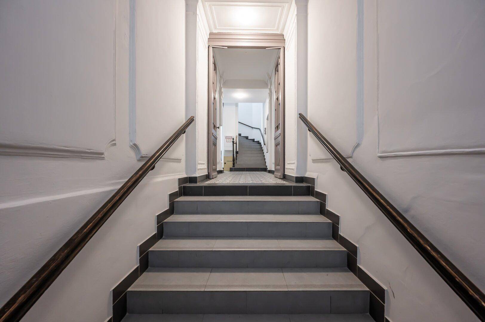 Eingangsbereich mit Treppe, Fliesenboden und klassischem Geländer, führt zu den oberen Etagen.
