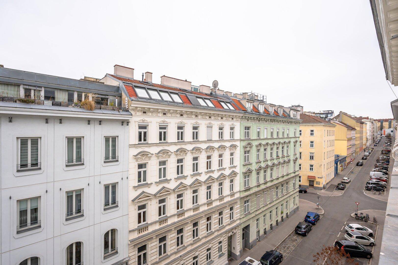 Panoramablick auf eine belebte Stadtstraße mit vielfältiger Architektur und vielen Fenstern.