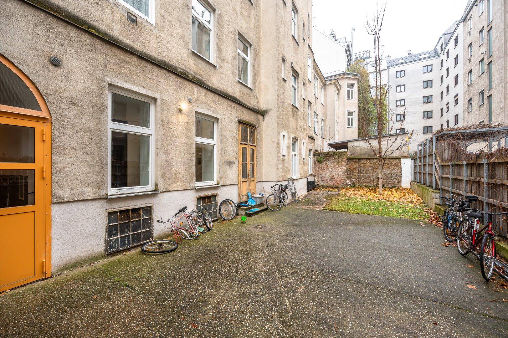 Innenhof eines Mehrfamilienhauses mit Abstellmöglichkeiten für Fahrräder und Grünfläche.