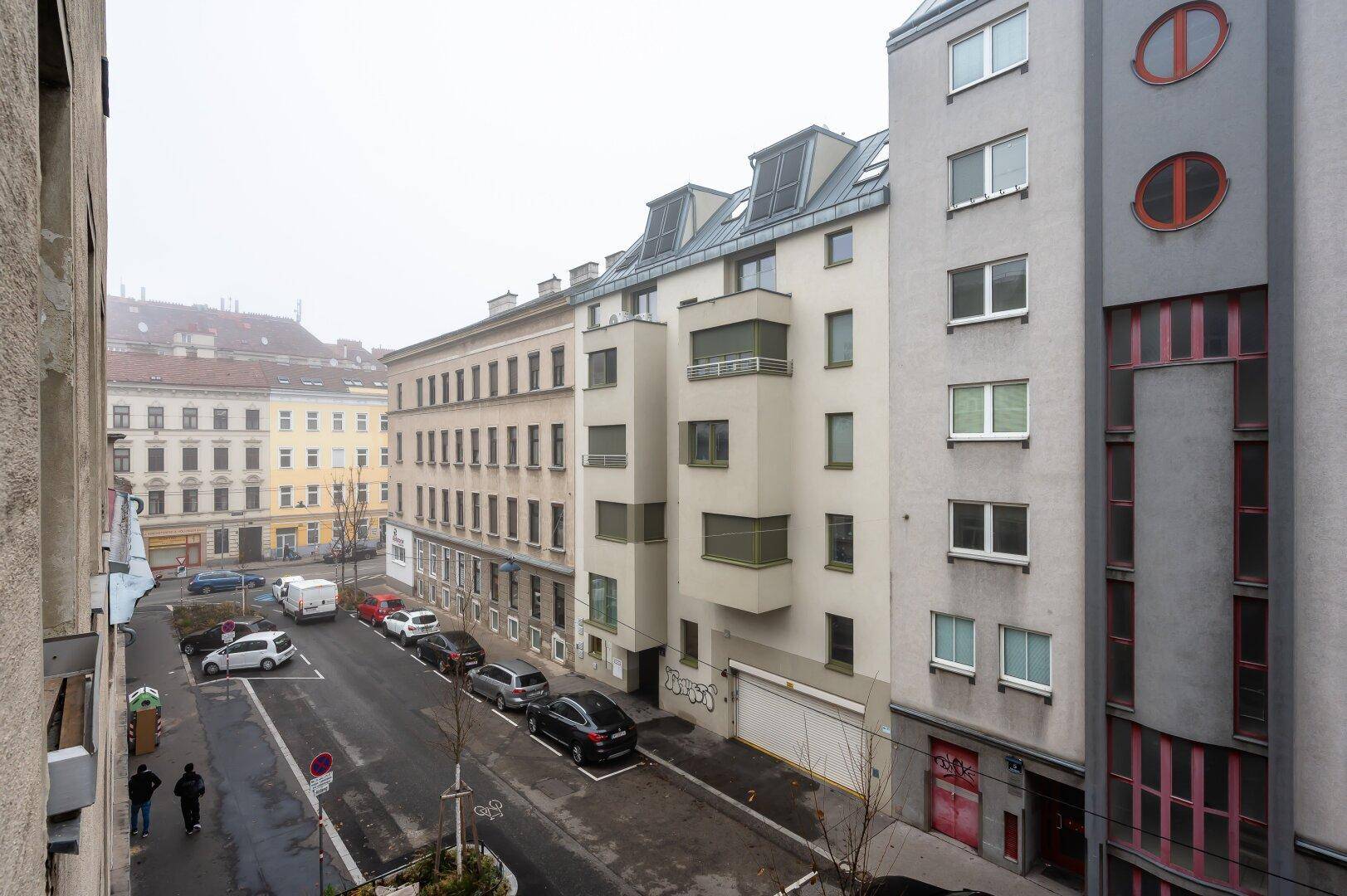 Blick auf eine städtische Straße mit verschiedenen Mehrfamilienhäusern an einem bewölkten Tag.