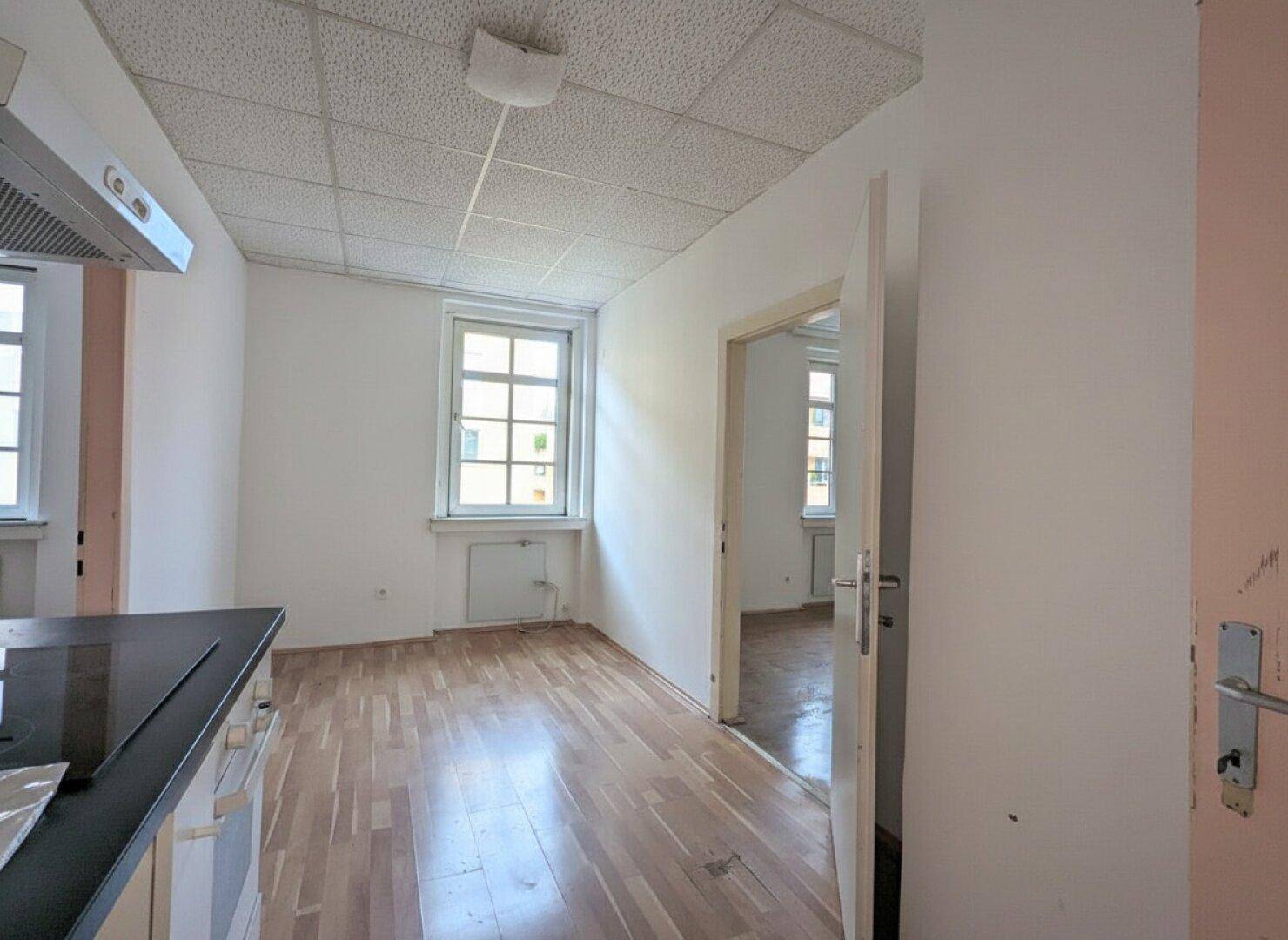 Helle Küche mit Holzfußboden, Fenster und einer kompakten Küchenzeile.