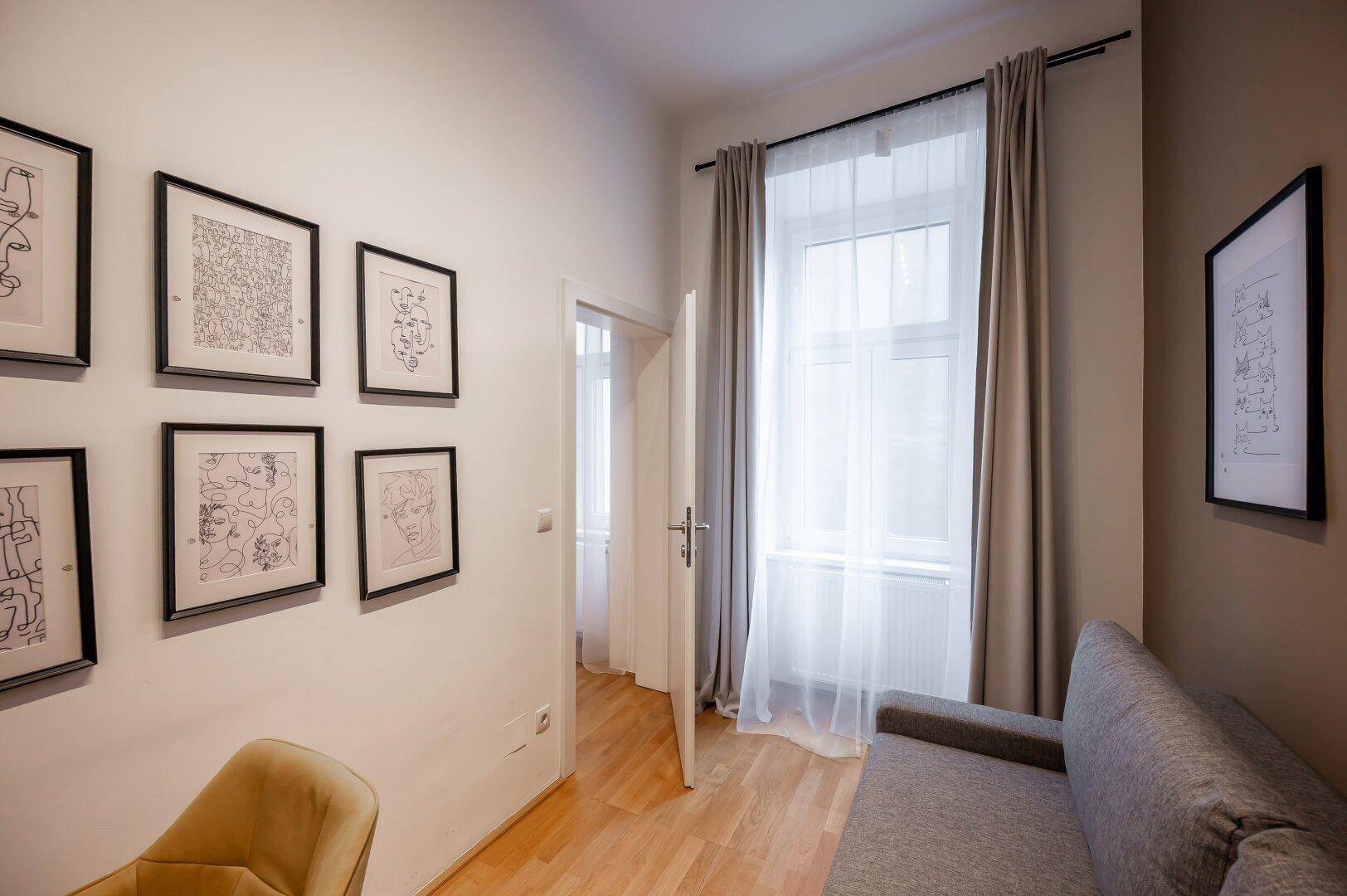 Gemütliches Arbeitszimmer mit Fenster, Holzboden und moderner Wanddekoration.