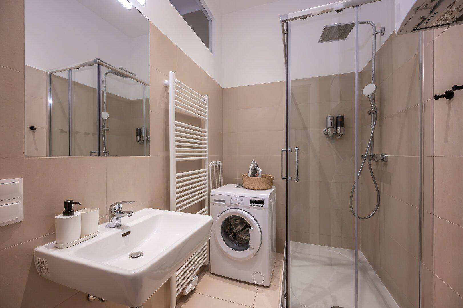 Modernes Badezimmer mit Dusche, Waschmaschine und beheiztem Handtuchhalter.