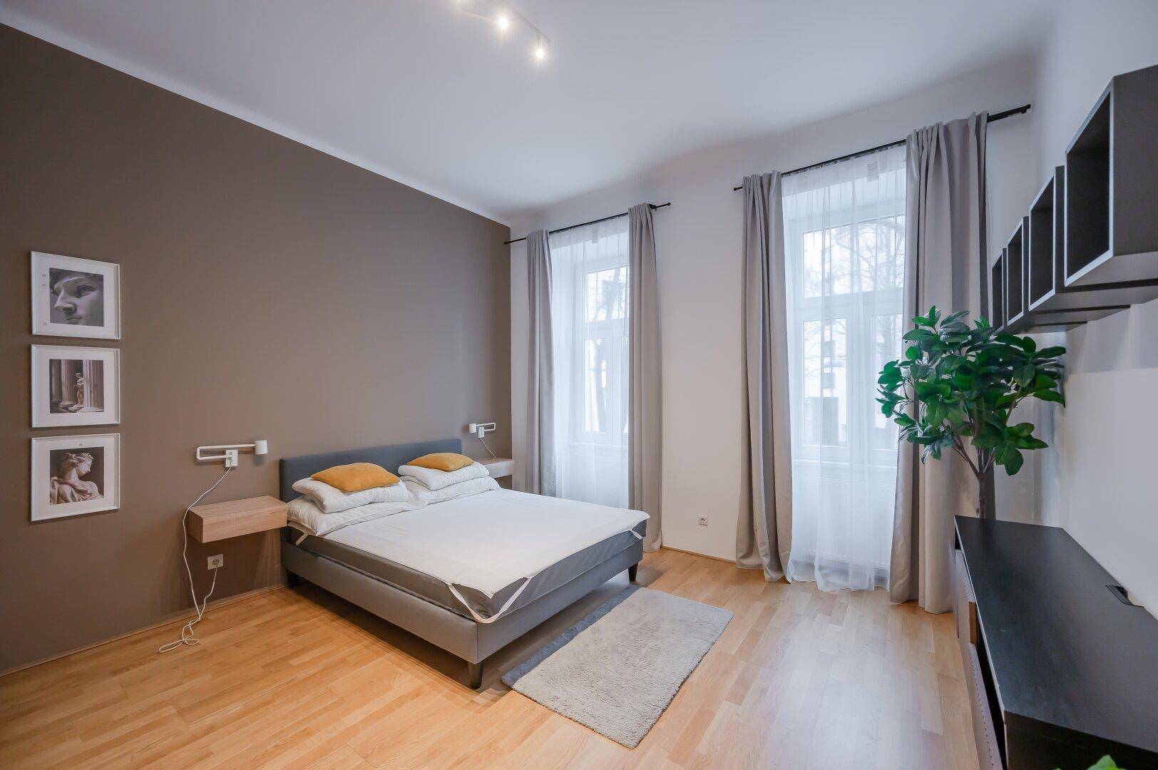 Helles Schlafzimmer mit Doppelbett, Holzboden und brauner Akzentwand.