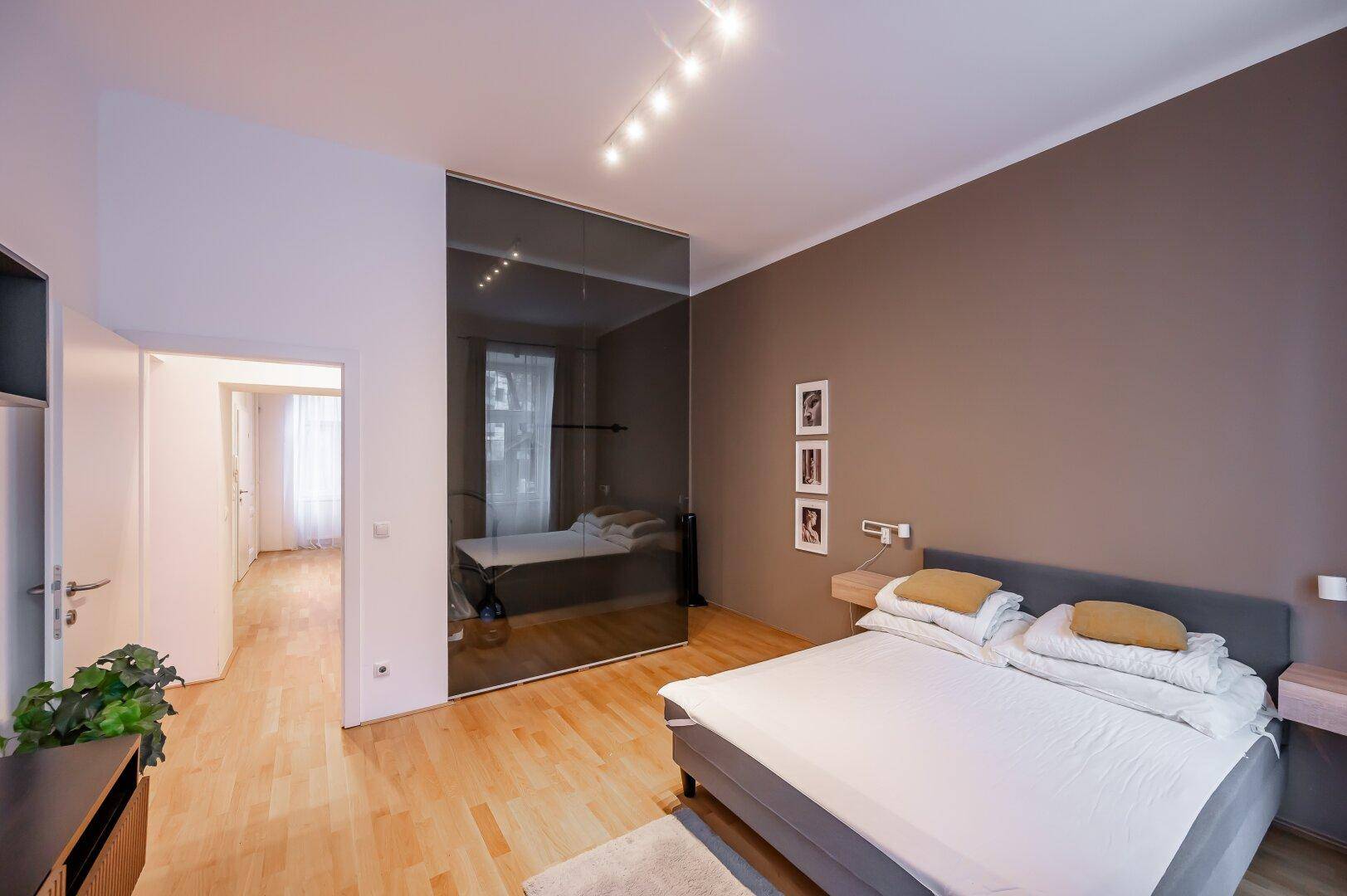 Geräumiges Schlafzimmer mit Holzboden und einer eleganten Spiegelfront.