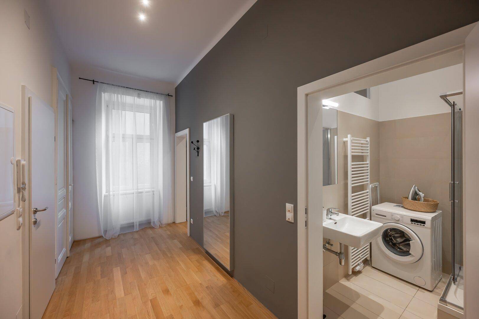 Heller Flur mit Holzboden und Zugang zu einem modernen Badezimmer.