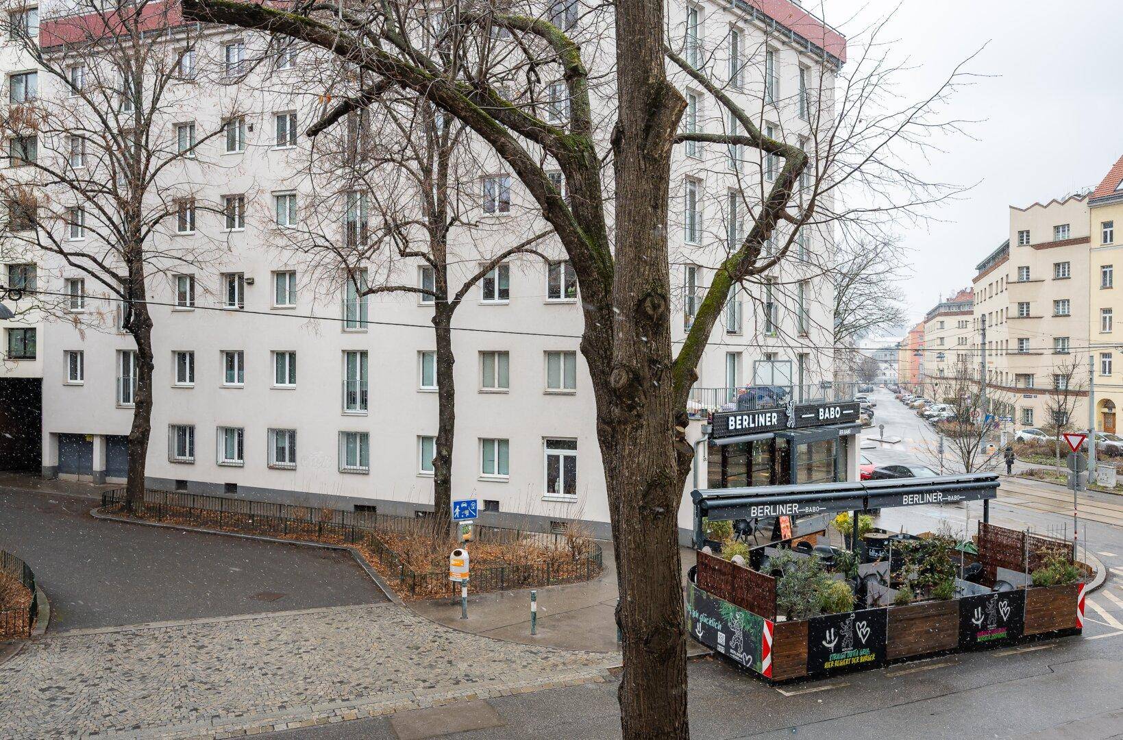 Stadtansicht mit Wohngebäude und einem Café im Erdgeschoss.