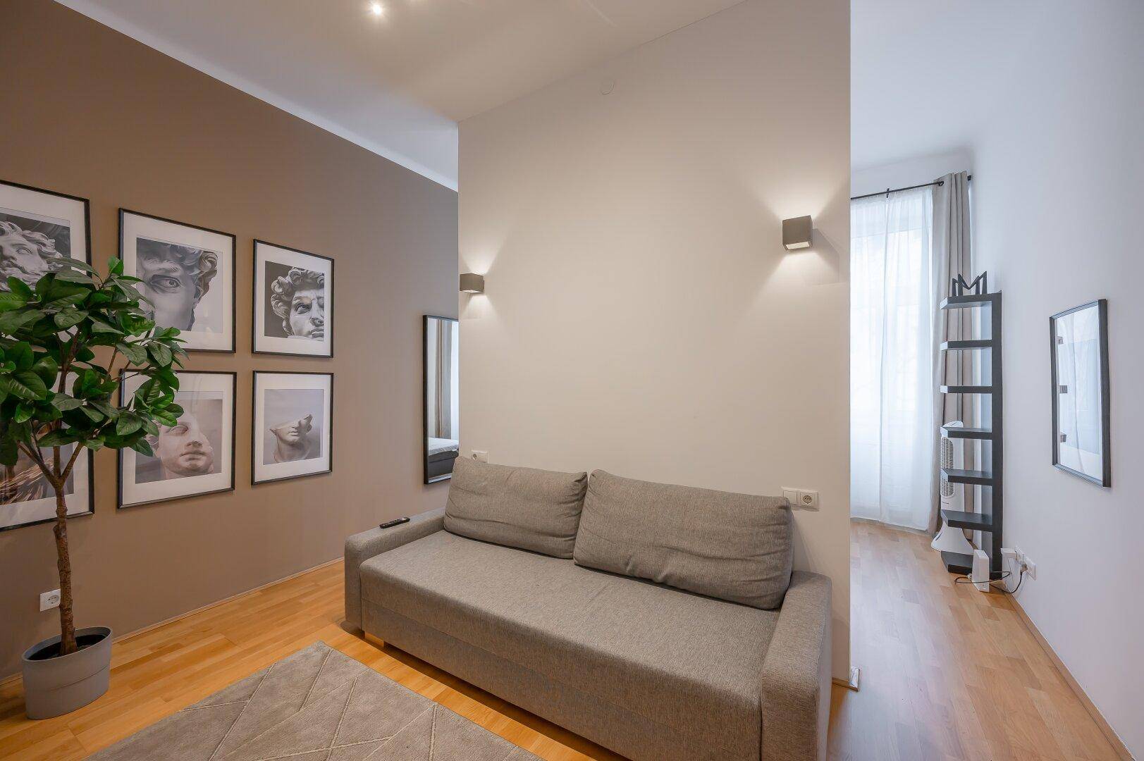 Gemütliches Wohnzimmer mit Sofa, Holzboden und dekorativen Schwarz-Weiß-Bildern an der Wand.