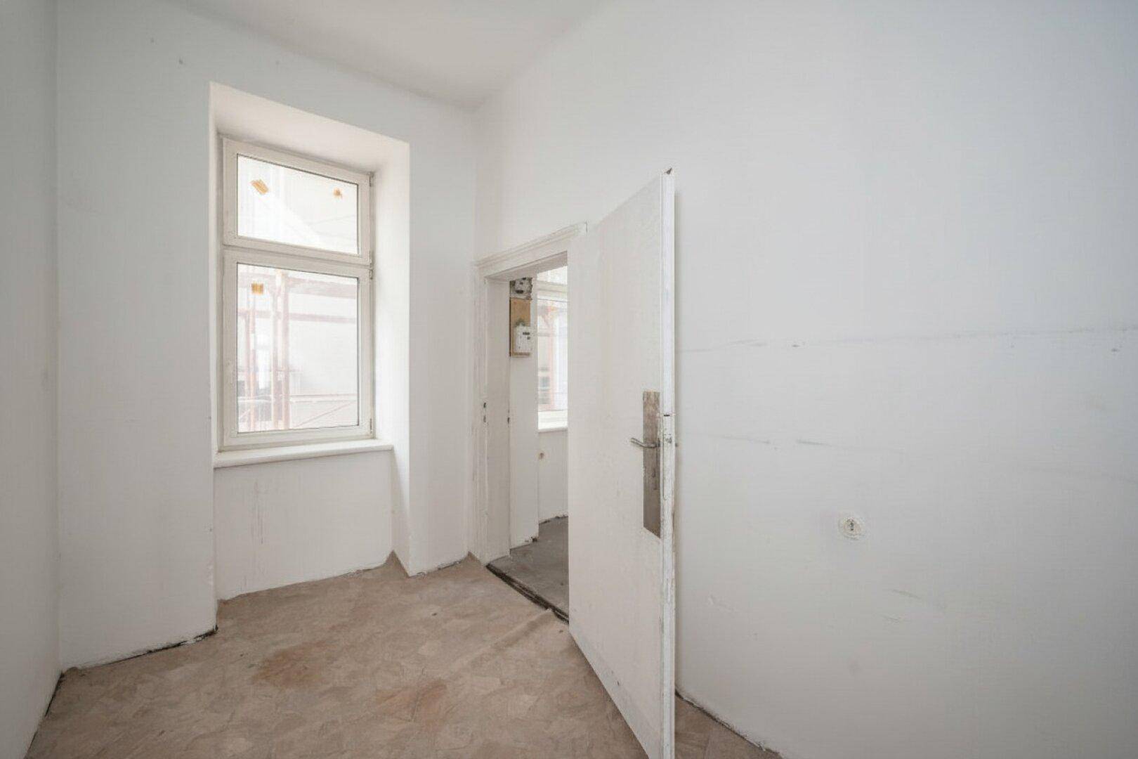 Kleiner leerer Raum mit Fenster und Betonboden, ideal für Abstellfläche oder Umbau.