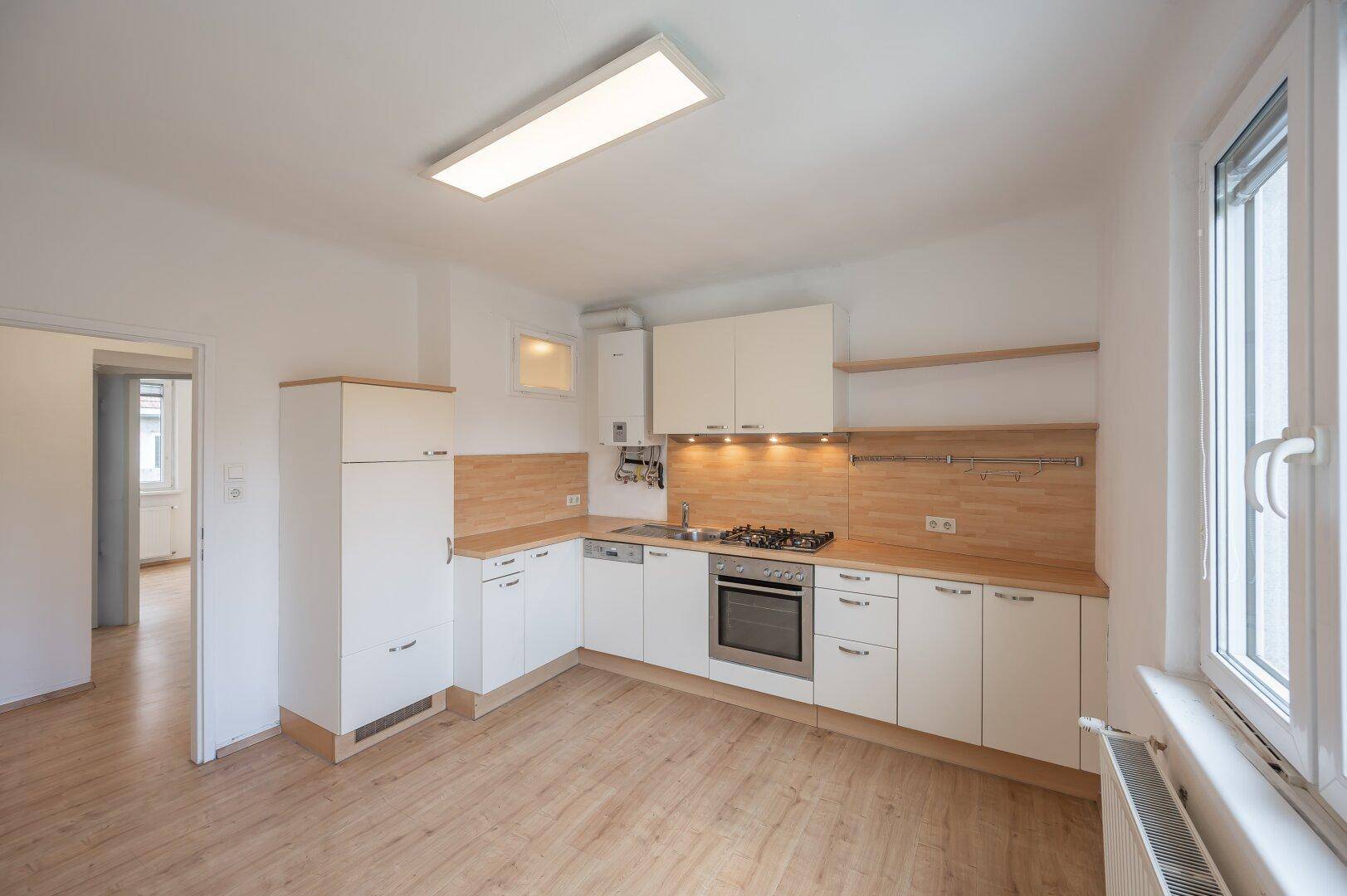 Funktionale Einbauküche mit hellen Fronten, Holzdetails und ausreichend Stauraum.