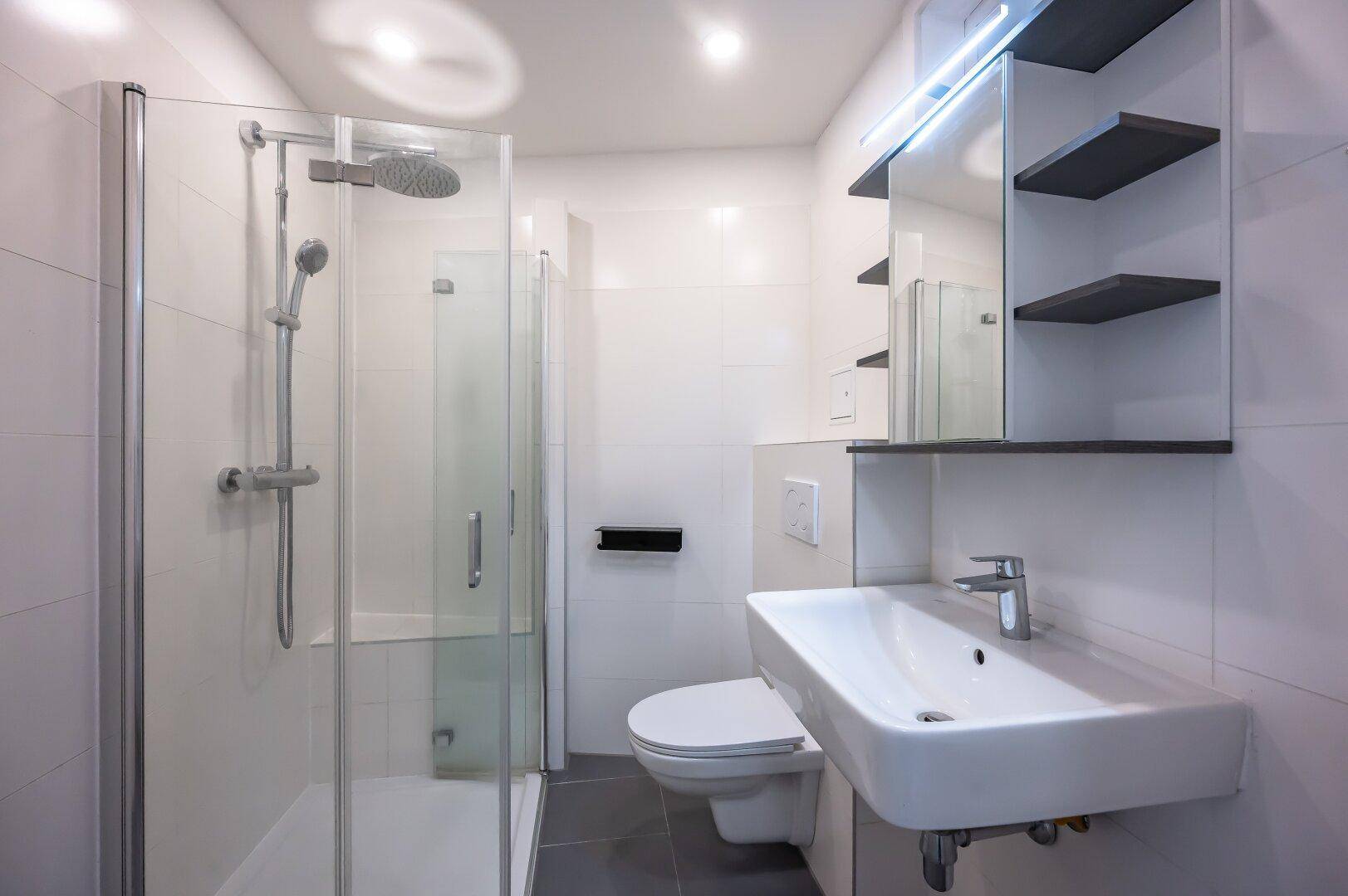 Modernes Badezimmer mit Dusche, wandhängendem WC und praktischem Spiegelschrank.