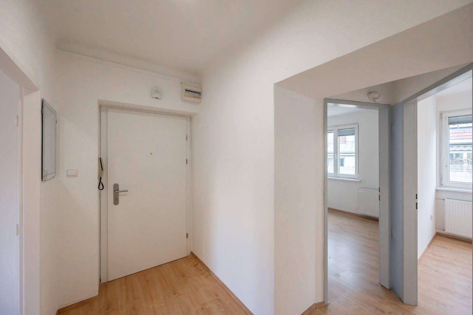 Heller Eingangsbereich mit Laminatboden und Zugang zu weiteren Zimmern der Wohnung.