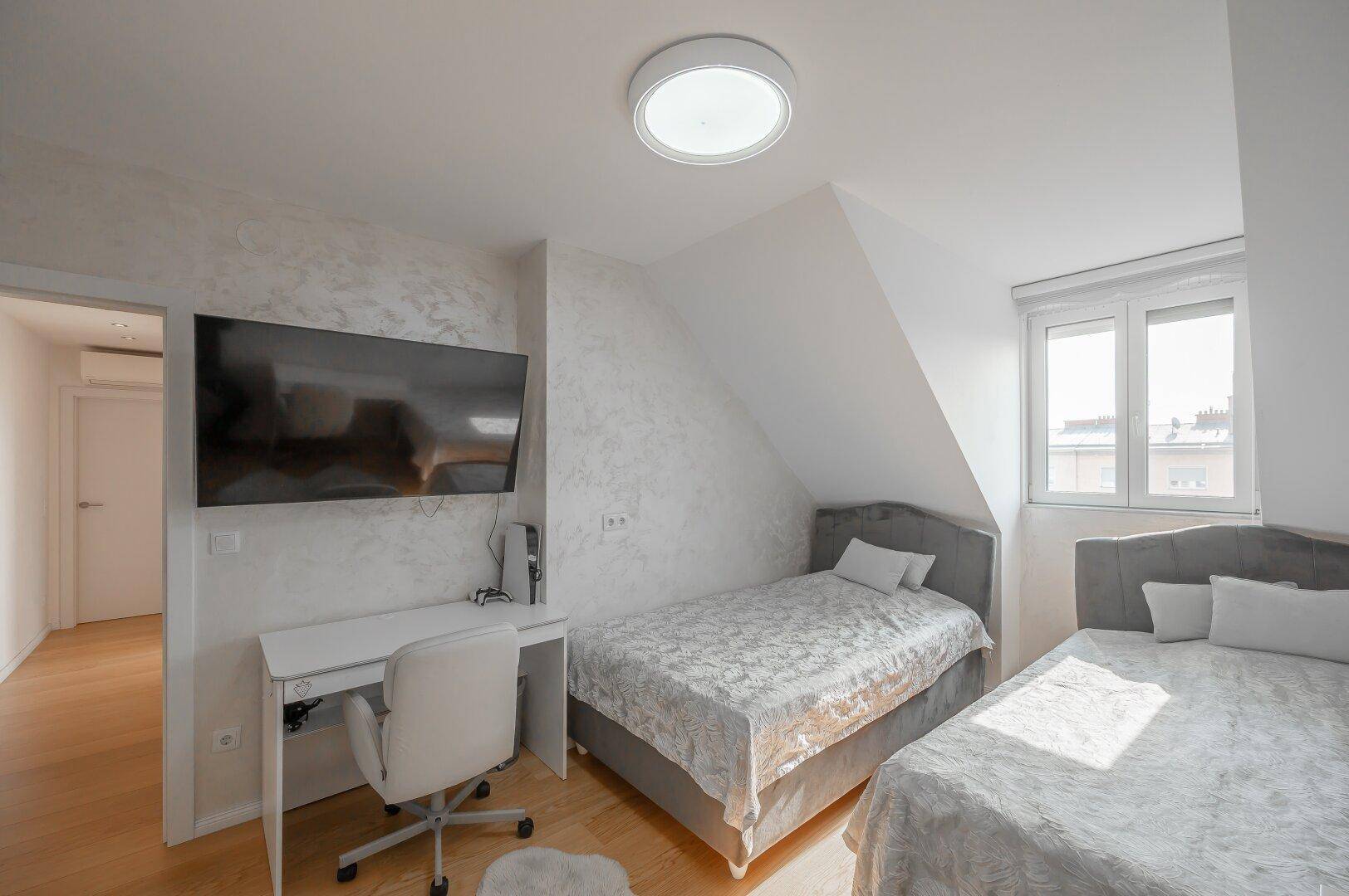 Schlafzimmer mit zwei Einzelbetten, Schreibtisch und Dachschräge.