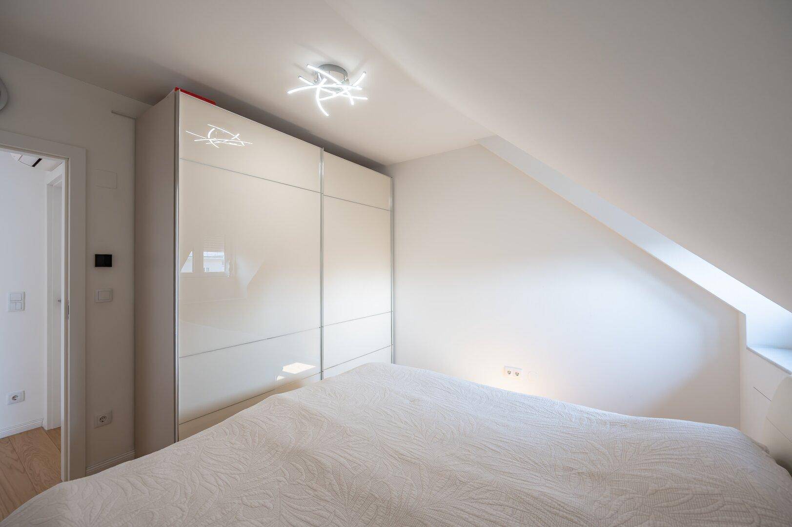 Schlafzimmer mit Doppelbett, großem Kleiderschrank und Dachschräge.