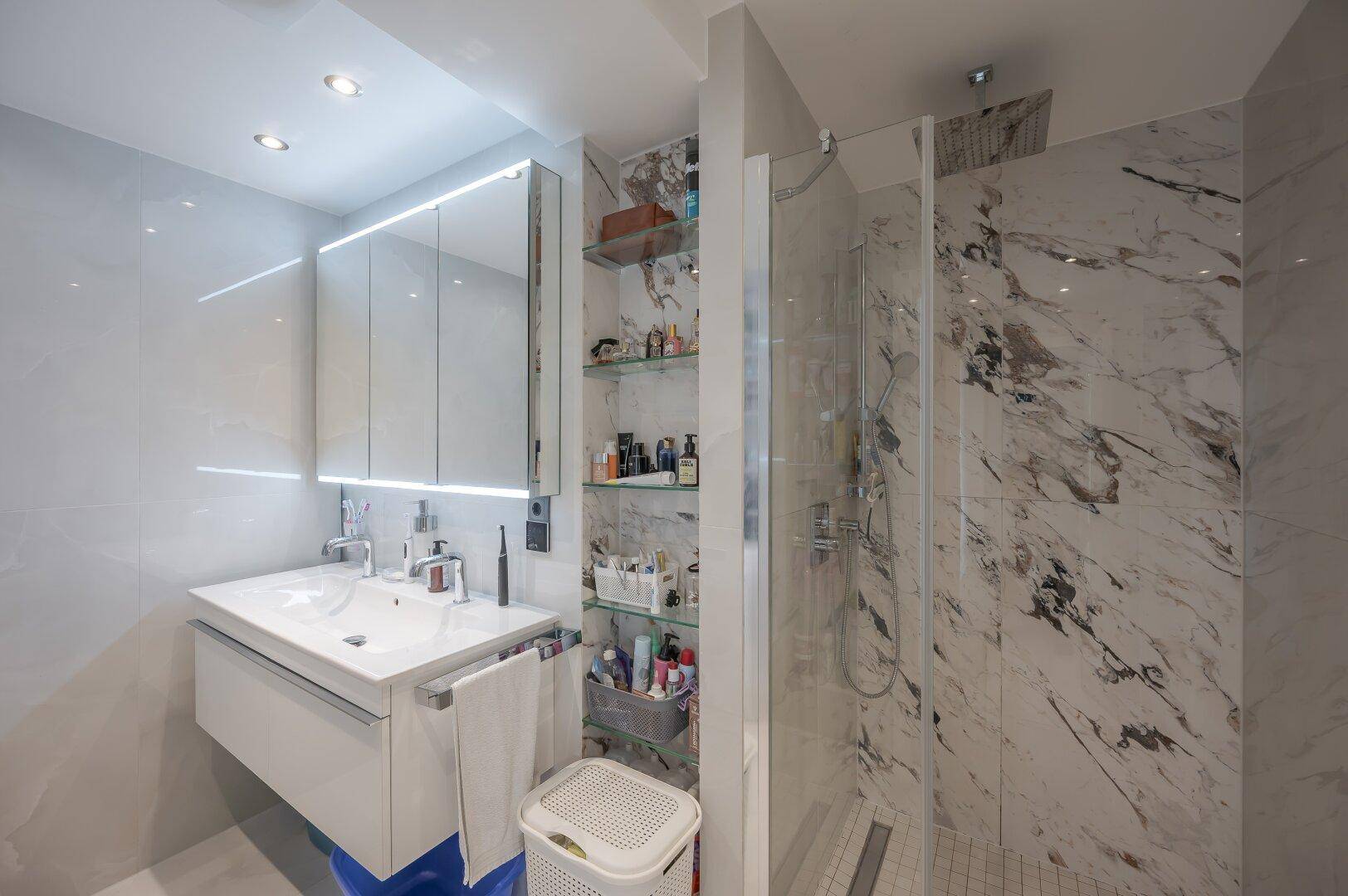 Elegantes Badezimmer mit begehbarer Dusche, modernem Waschtisch und Marmorfliesen.