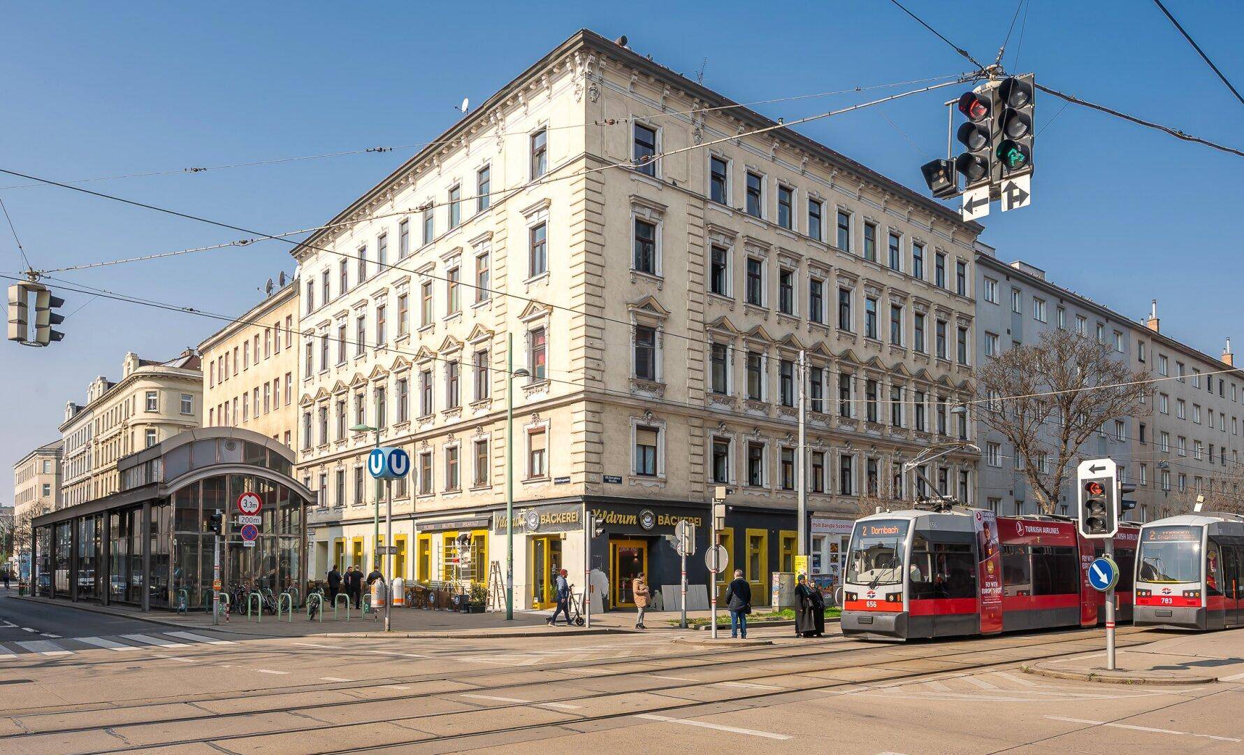 Klassisches Eckgebäude mit Geschäften im Erdgeschoss an einer städtischen Kreuzung.