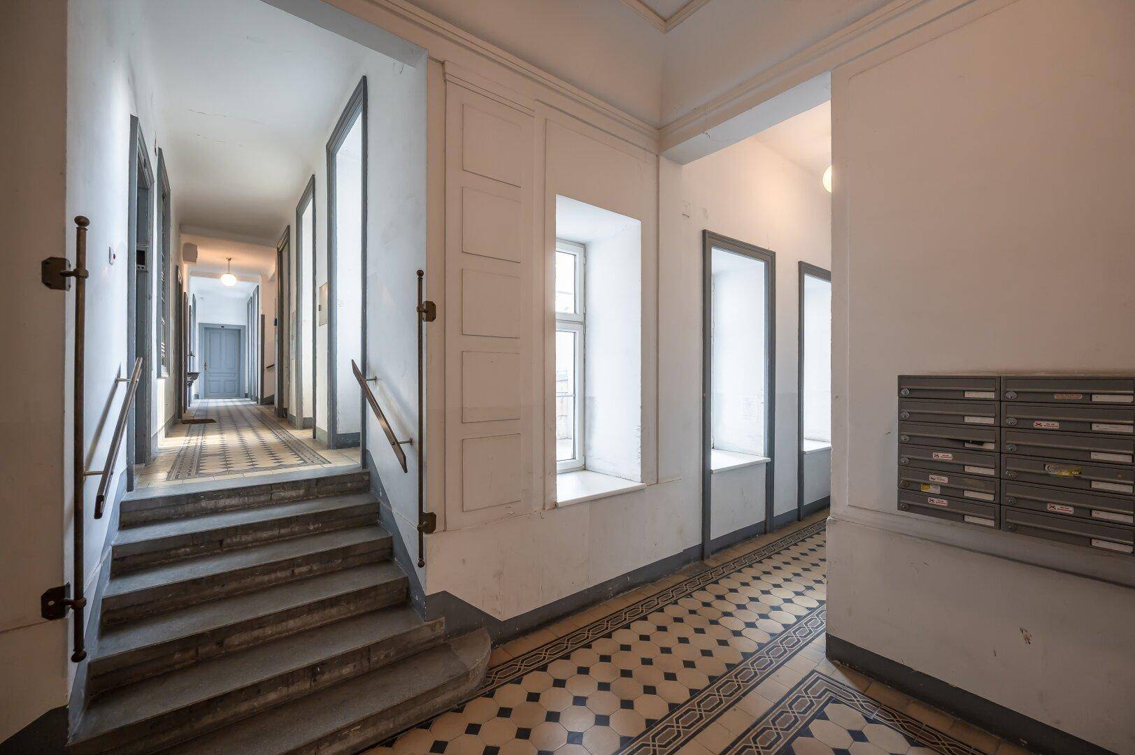 Historisches Treppenhaus mit kunstvollen Fliesen und hohen Decken.