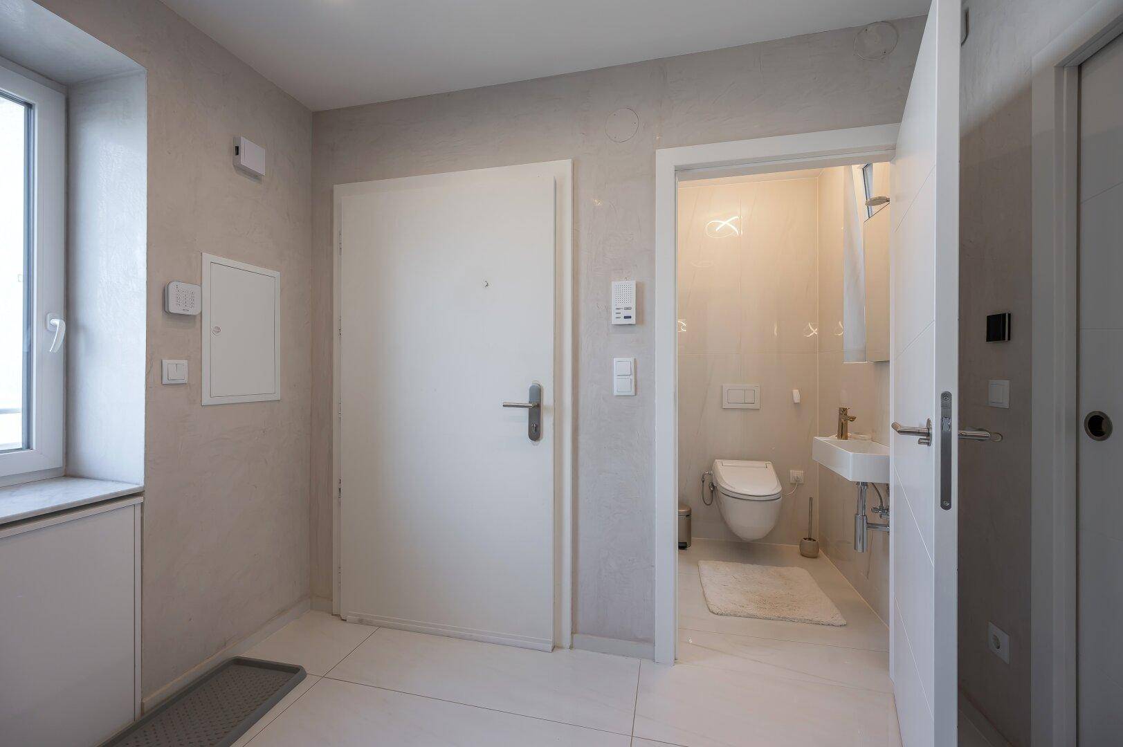 Separates Gäste-WC mit kleinem Waschbecken und Fenster.