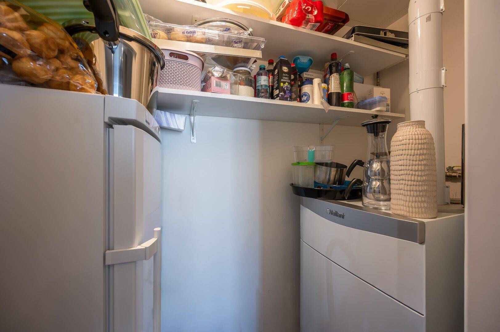 Praktischer Abstellraum mit Warmwasserbereiter und Regalen für Vorräte.
