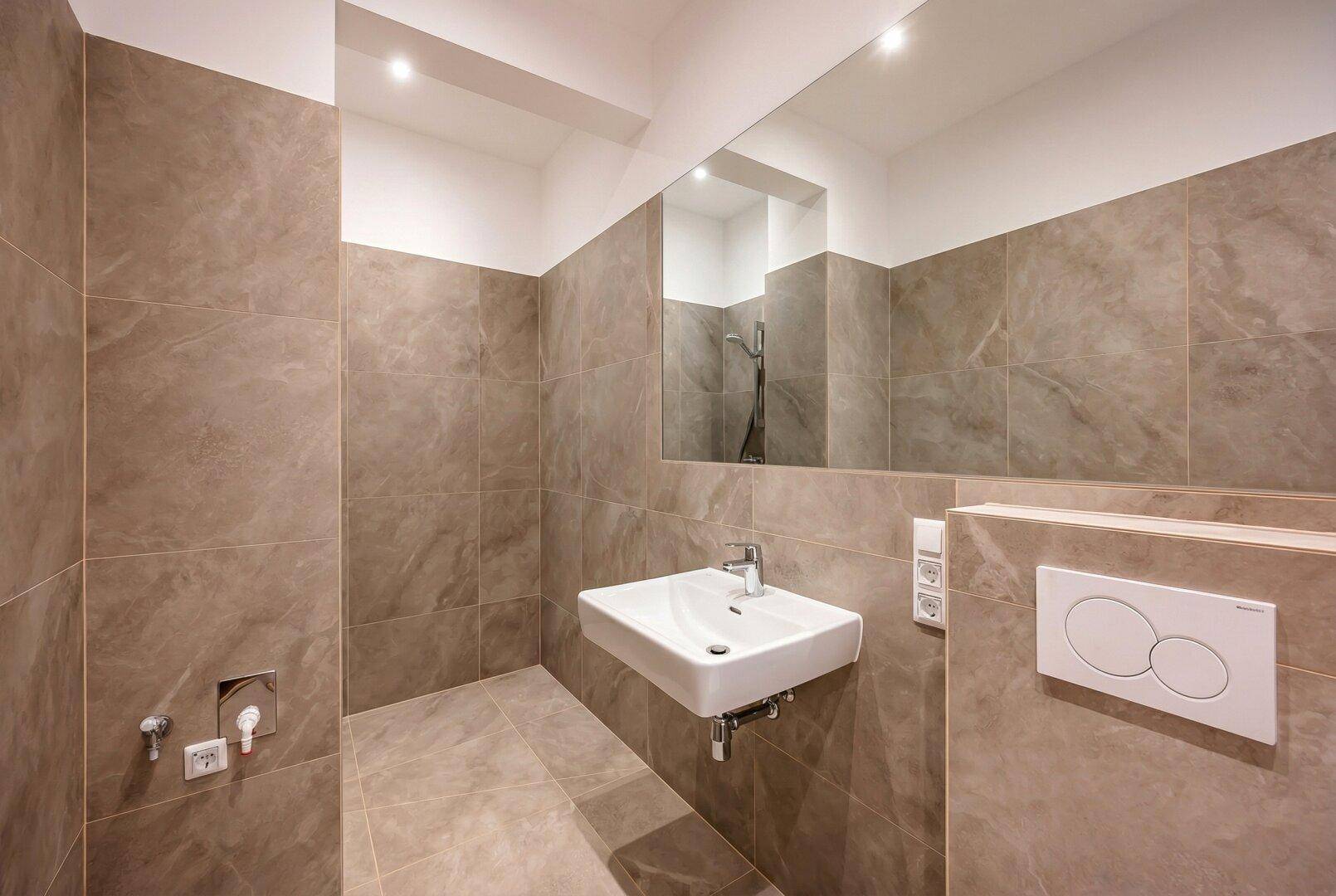Zeitgemäßes Badezimmer mit großem Spiegel, wandhängendem WC und modernem Waschbecken.