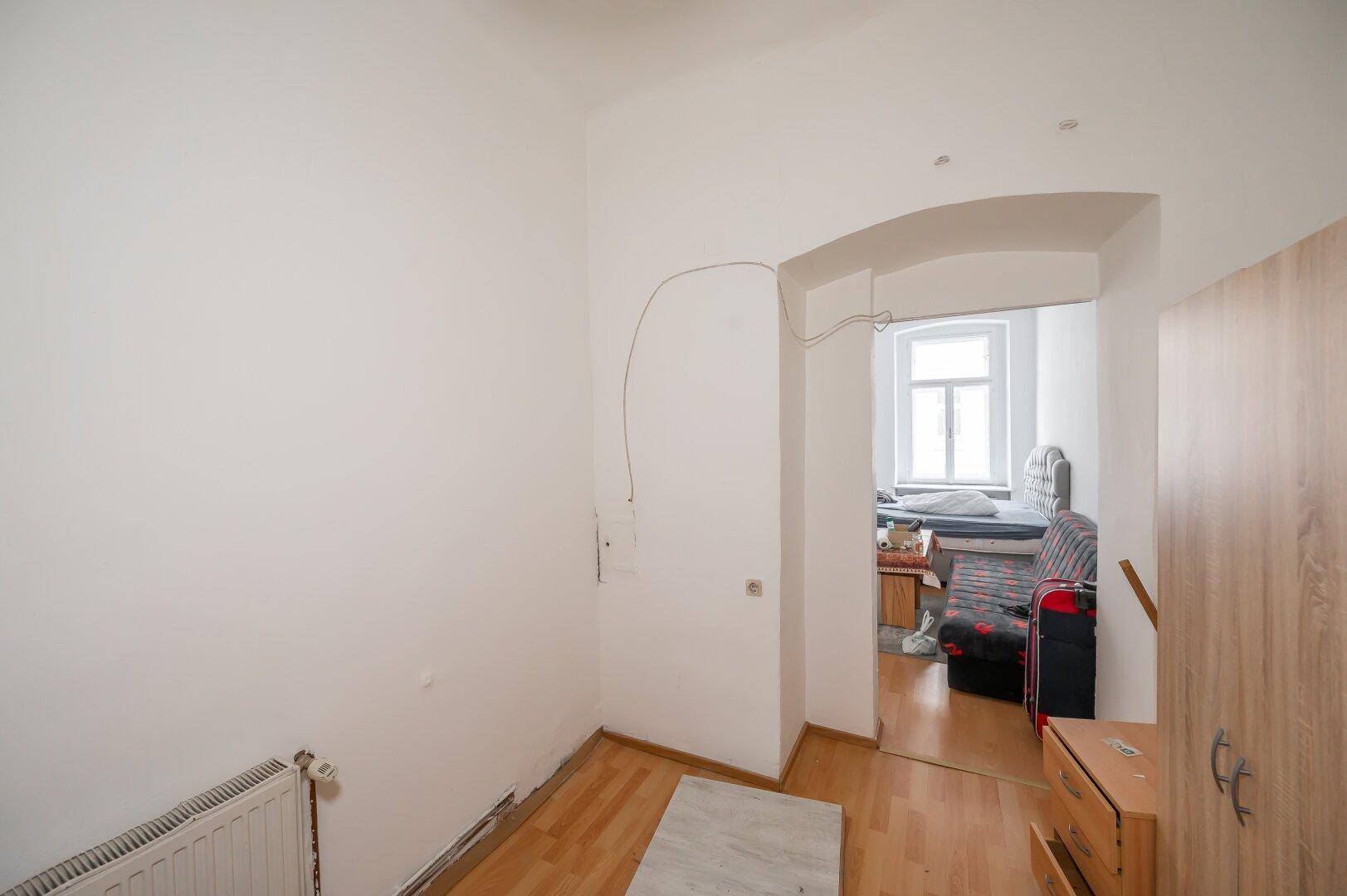 Heller Flur mit Holzboden und Durchgang zu einem weiteren Zimmer.