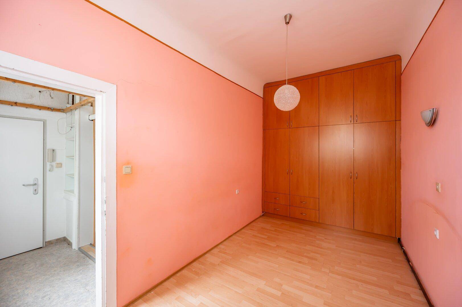 Schlafzimmer mit großem, eingebautem Holzschrank und Holzboden, bereit zur individuellen Gestaltung.