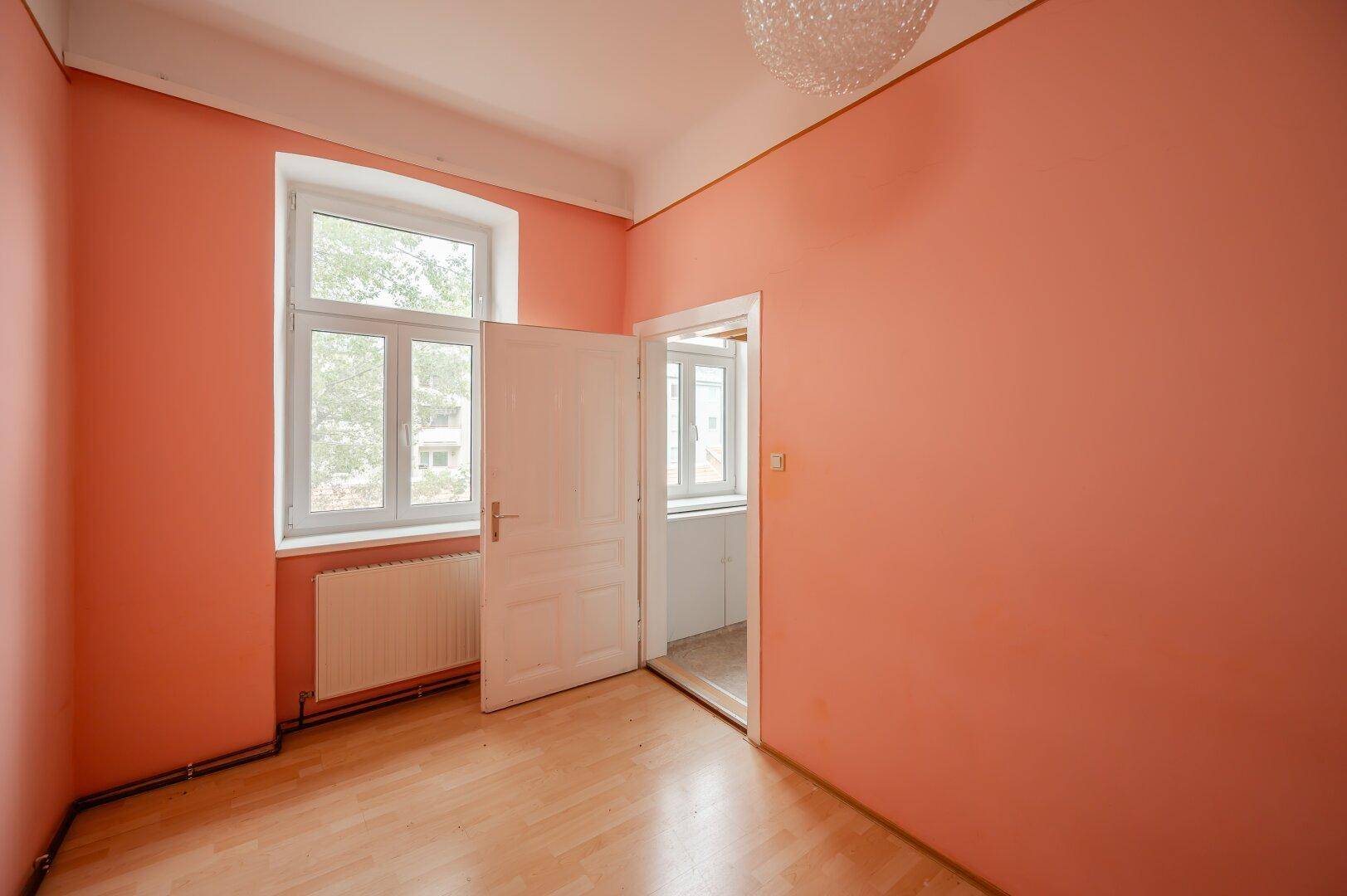 Helles Zimmer mit Fenster und Zugang zu einem weiteren Bereich, ideal für flexible Nutzung.
