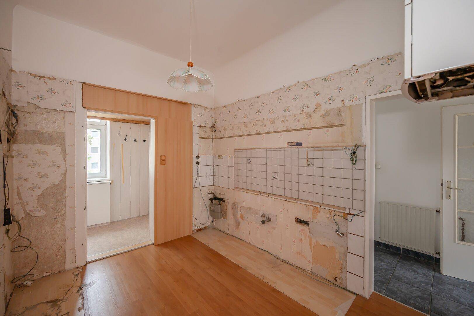 Küche im Renovierungszustand mit alten Fliesen und Holzboden, wartet auf eine umfassende Modernisierung.